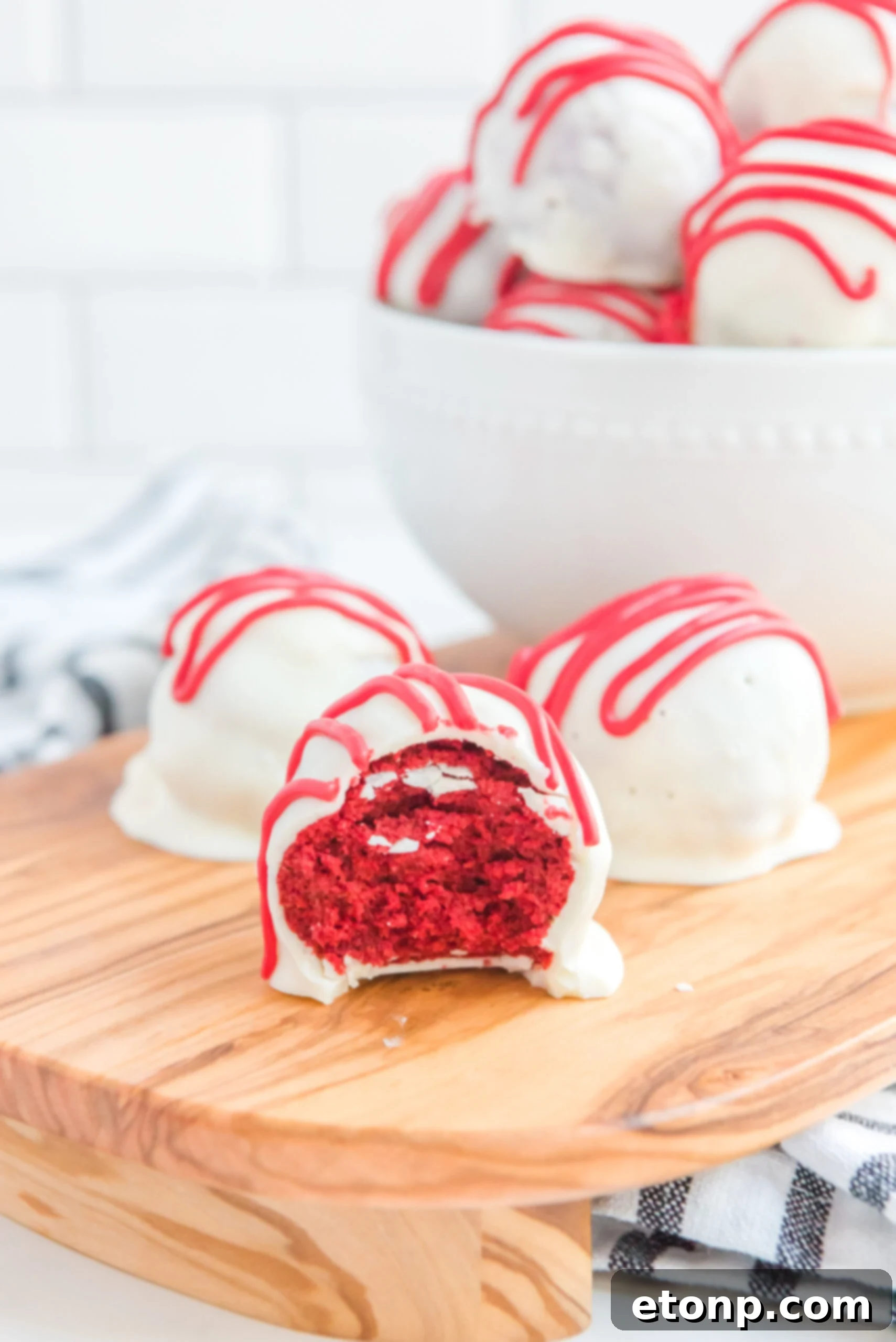 Three cake balls on a wooden serving tray, one has a bite removed showing the inside.