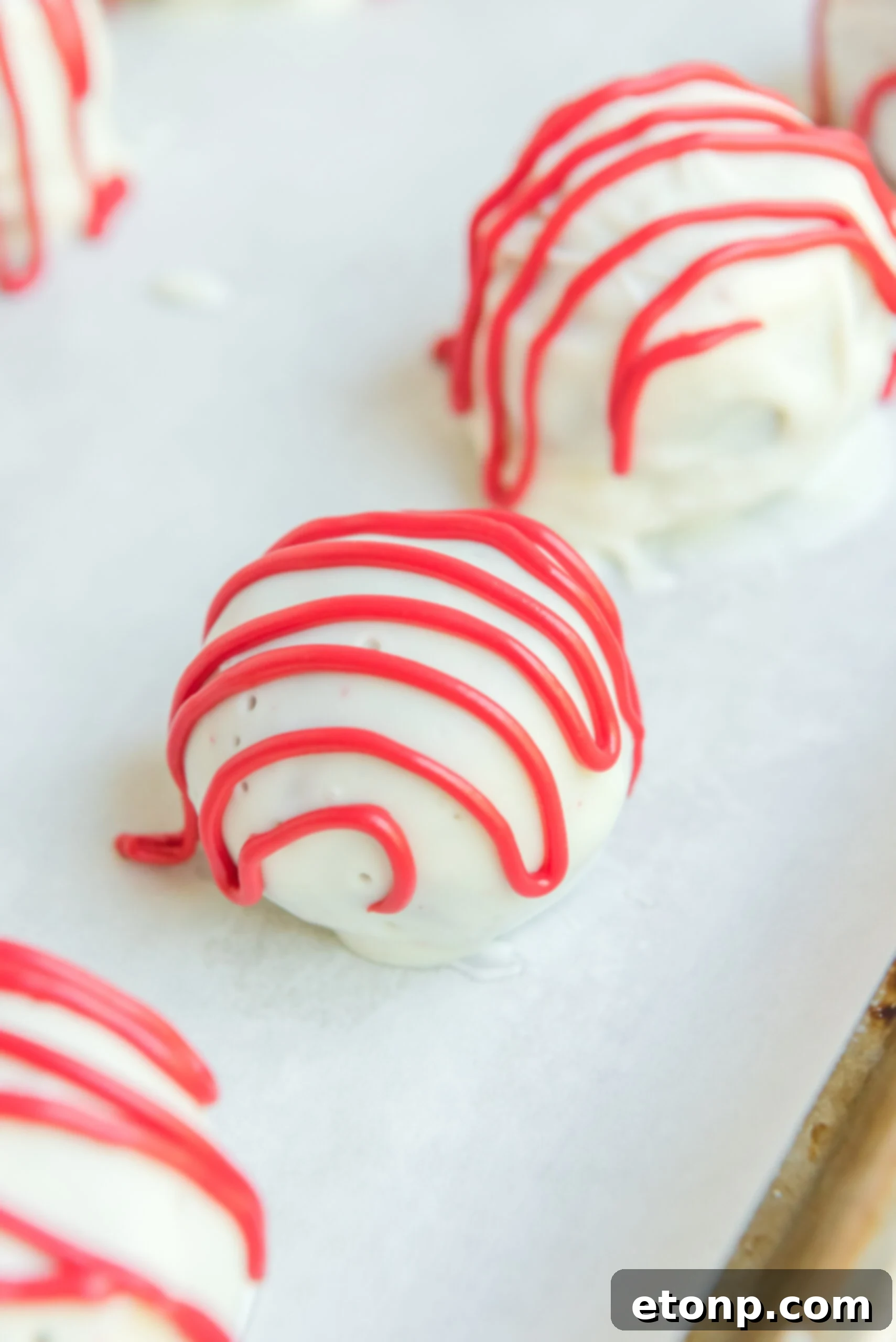 Close up shot of the red drizzle on top of a red velvet cake ball.
