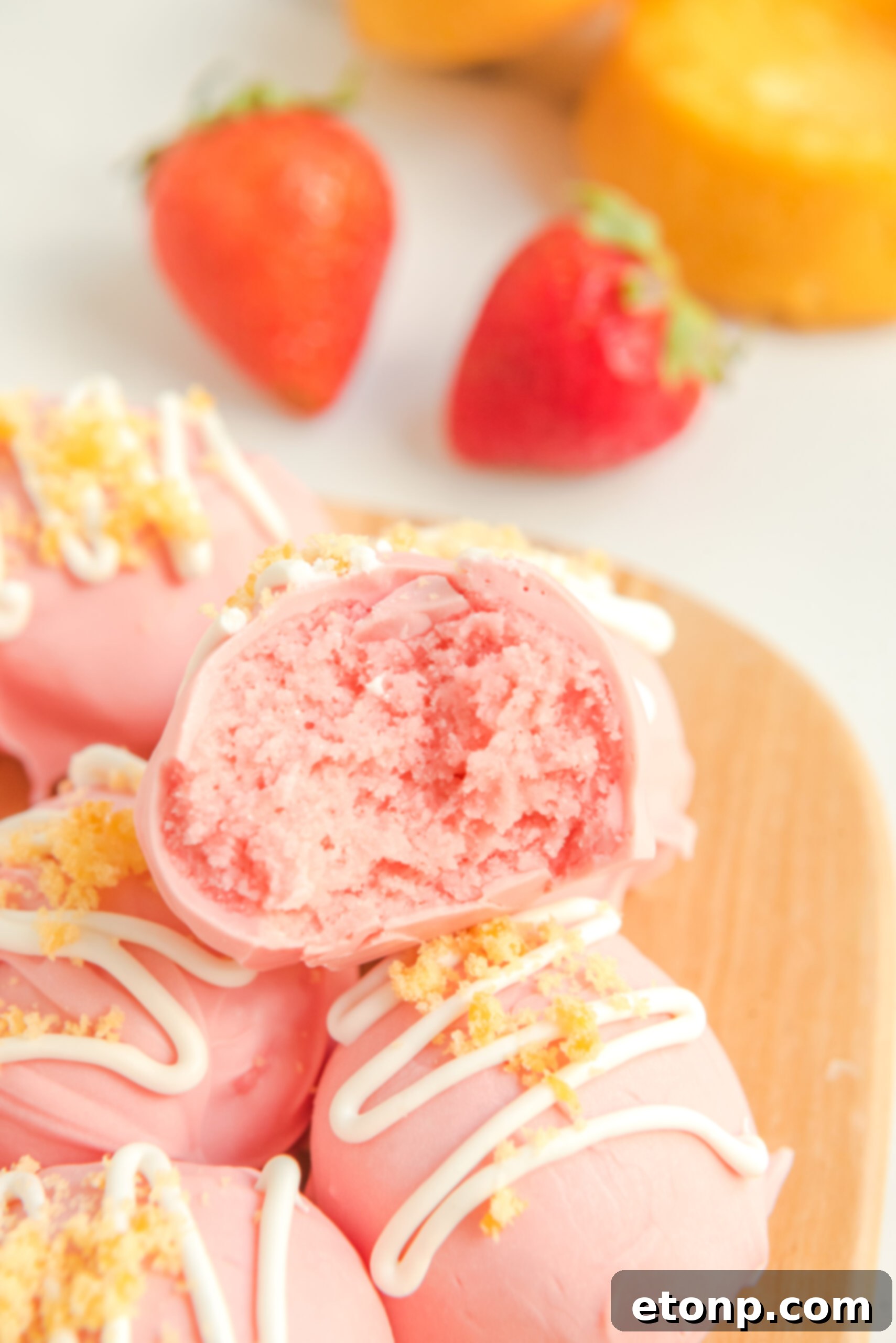 Close-up detailed view of the creamy, pink center of a bitten strawberry shortcake truffle.