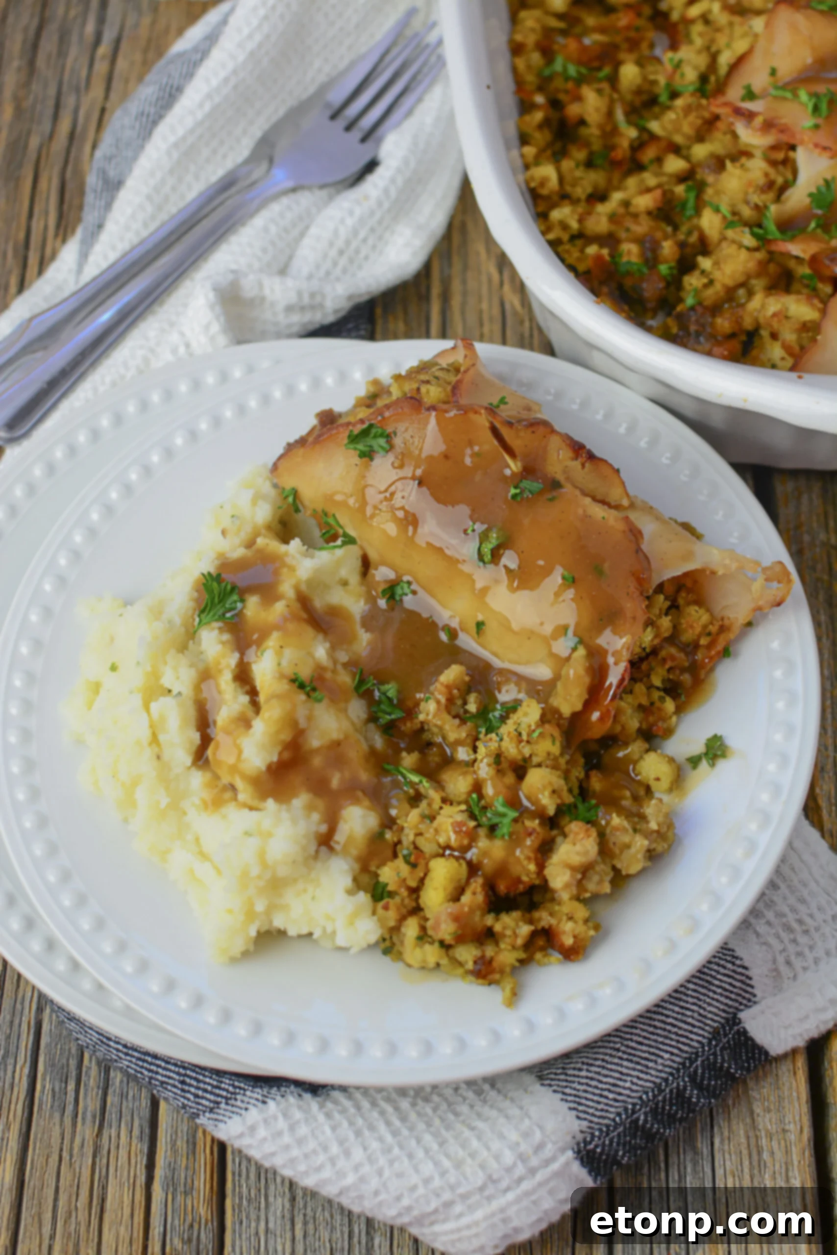 Turkey Stuffing Roll Ups on a white plate with mashed potatoes on a wood table