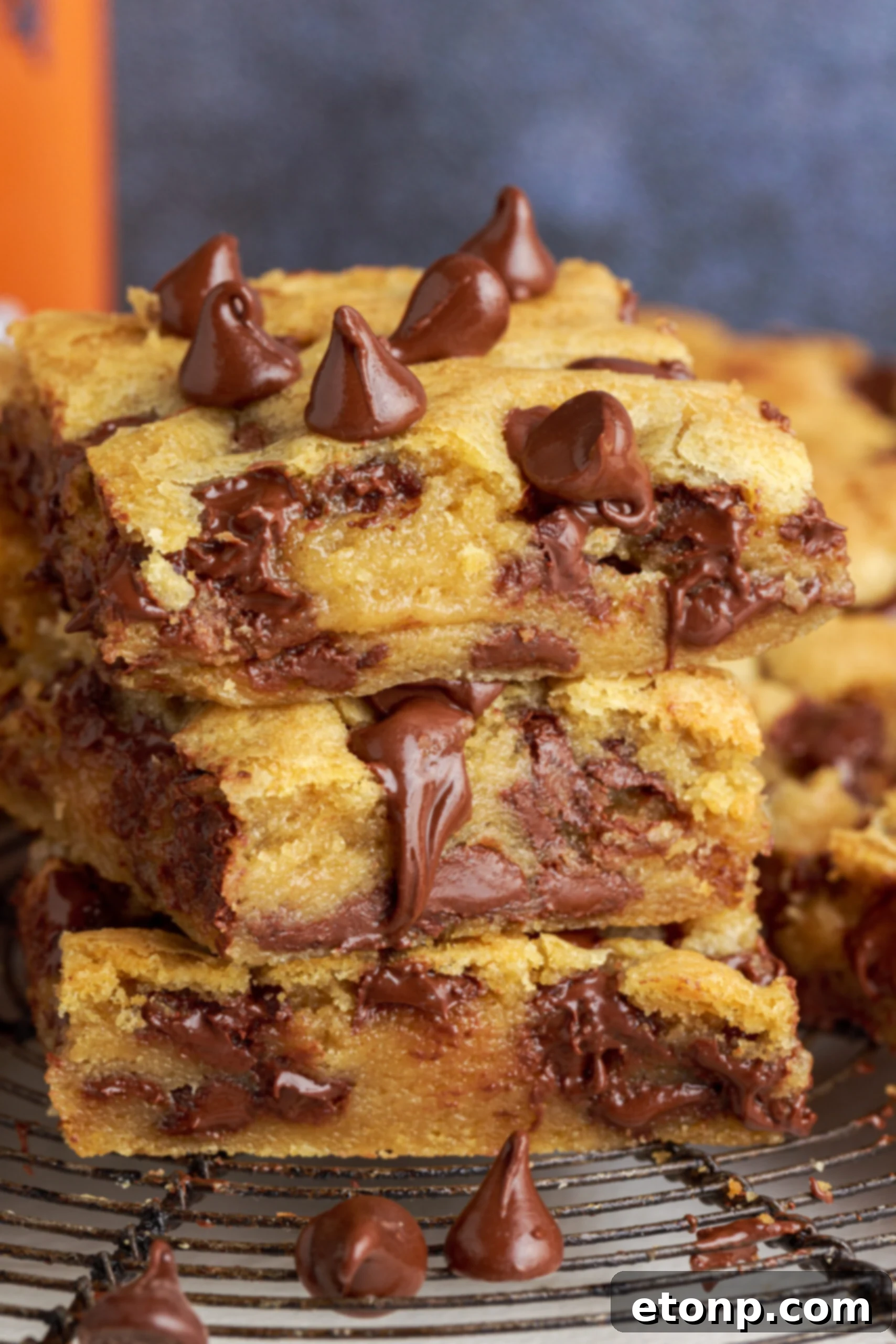 Side view of three stacked gooey chocolate chip cookie bars, showcasing their soft texture and melted chocolate chips.