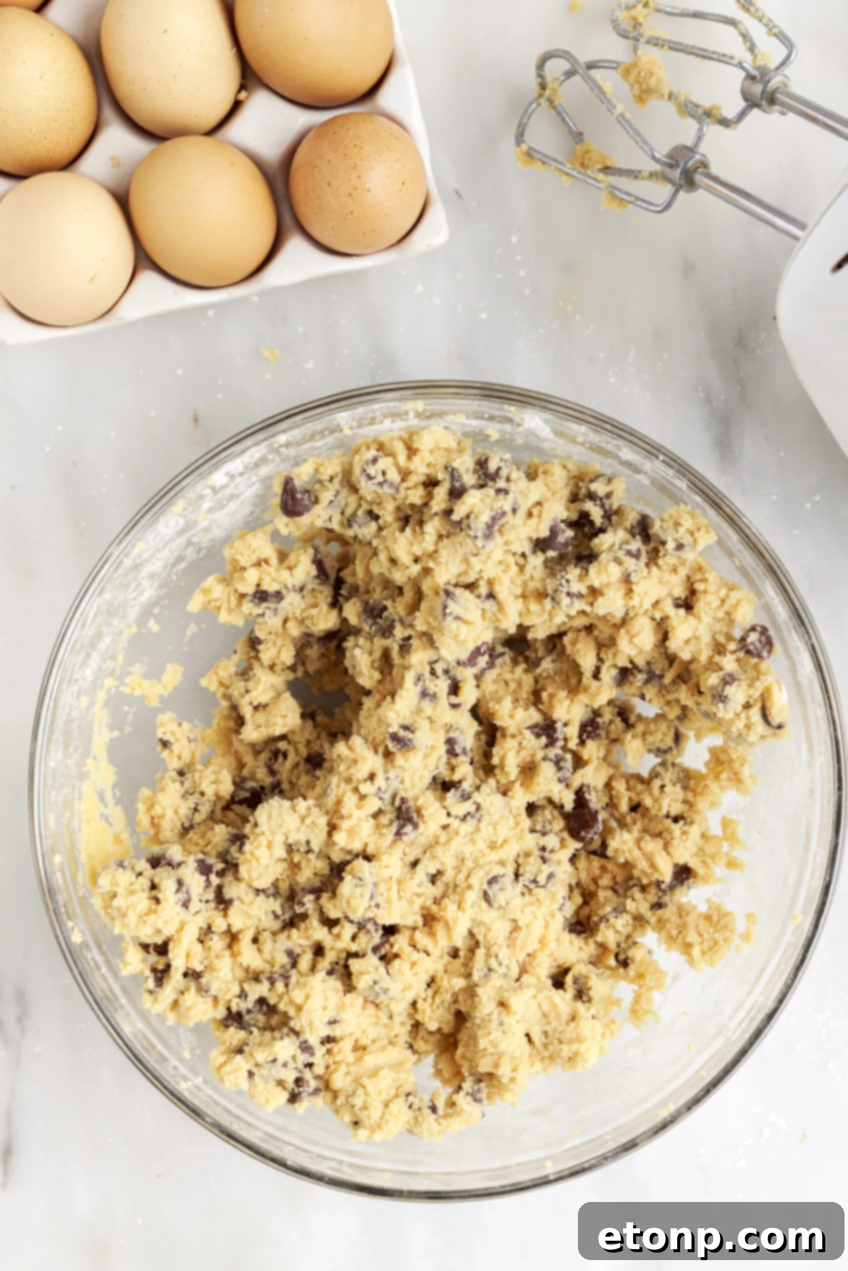 Electric mixer creaming softened butter, light brown sugar, and granulated sugar in a mixing bowl until light and fluffy.