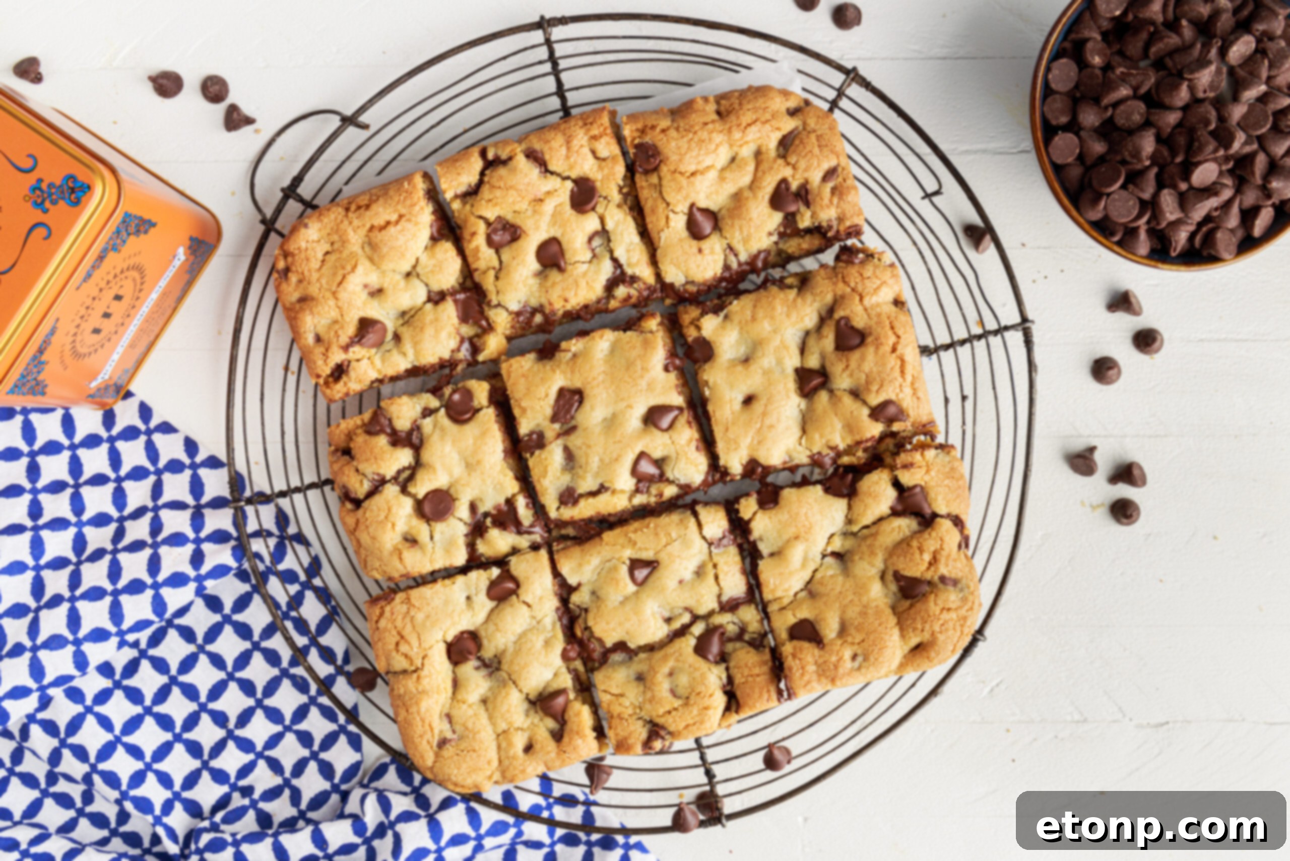 Overhead view of gooey chocolate chip cookie bars, freshly cut into nine perfect squares and arranged on a wire rack to cool.
