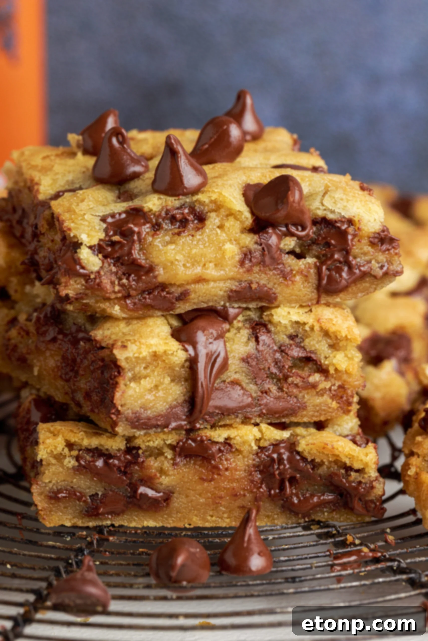 A perfectly arranged stack of three homemade gooey chocolate chip cookie bars, ready to be enjoyed.