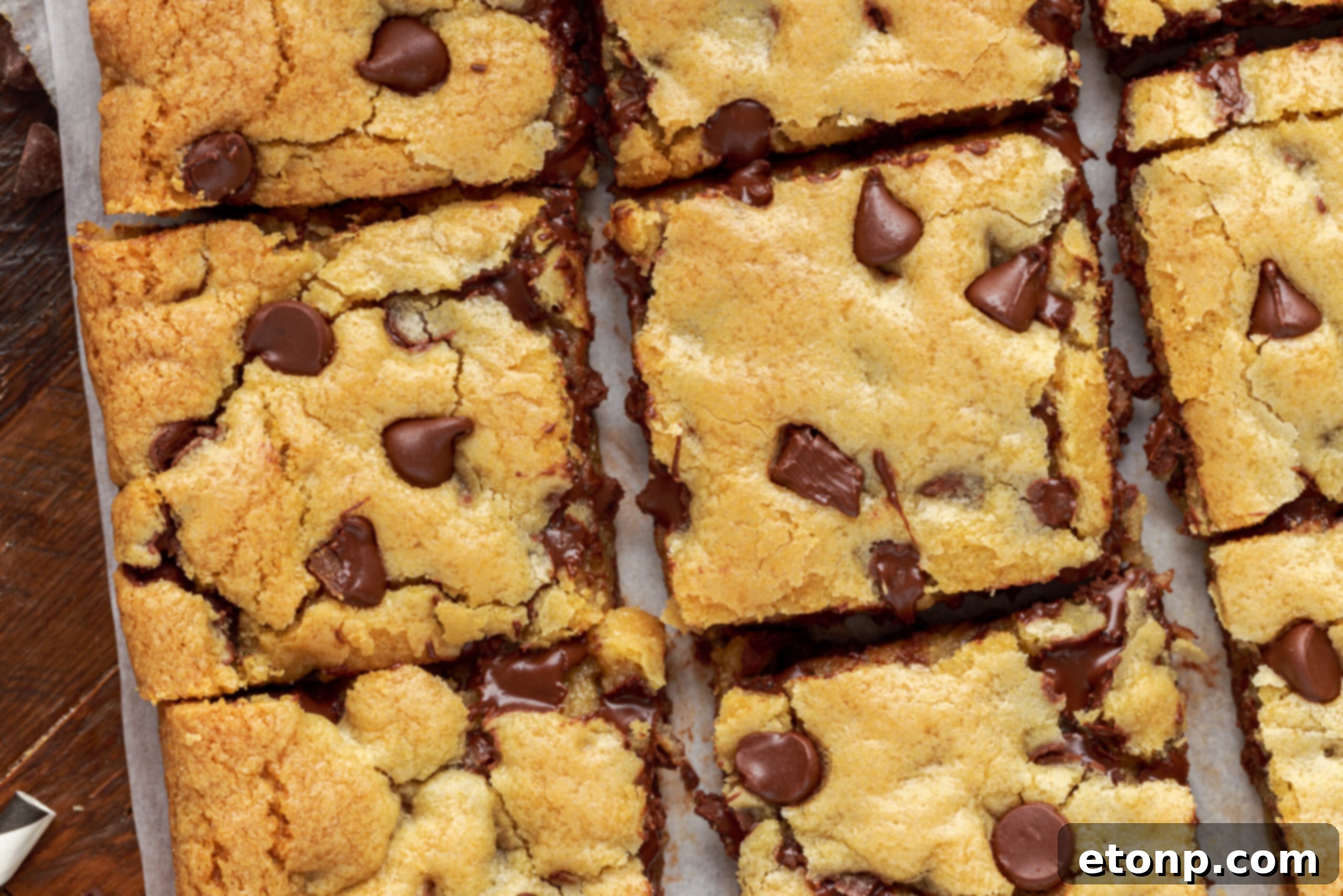 Overhead shot of freshly baked chocolate chip cookie bars, warm and glistening with melted chocolate, ready to be cut.