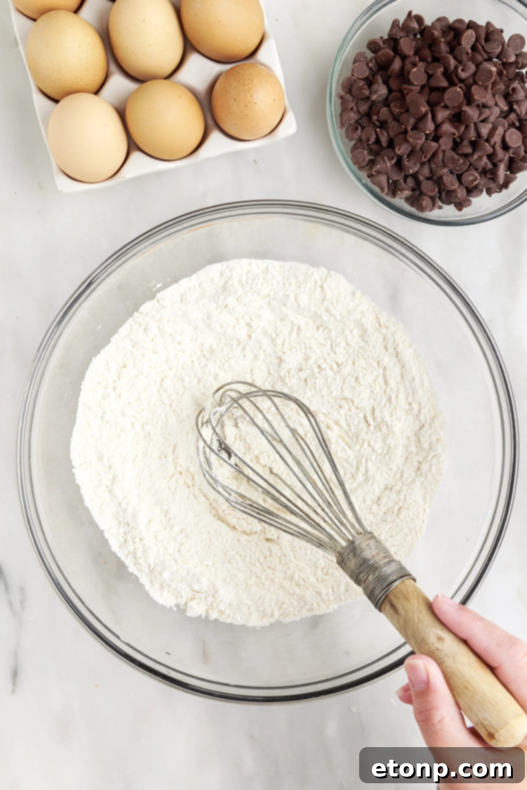 Close-up of unbaked cookie dough spread evenly in a parchment-lined baking pan, ready for the oven.