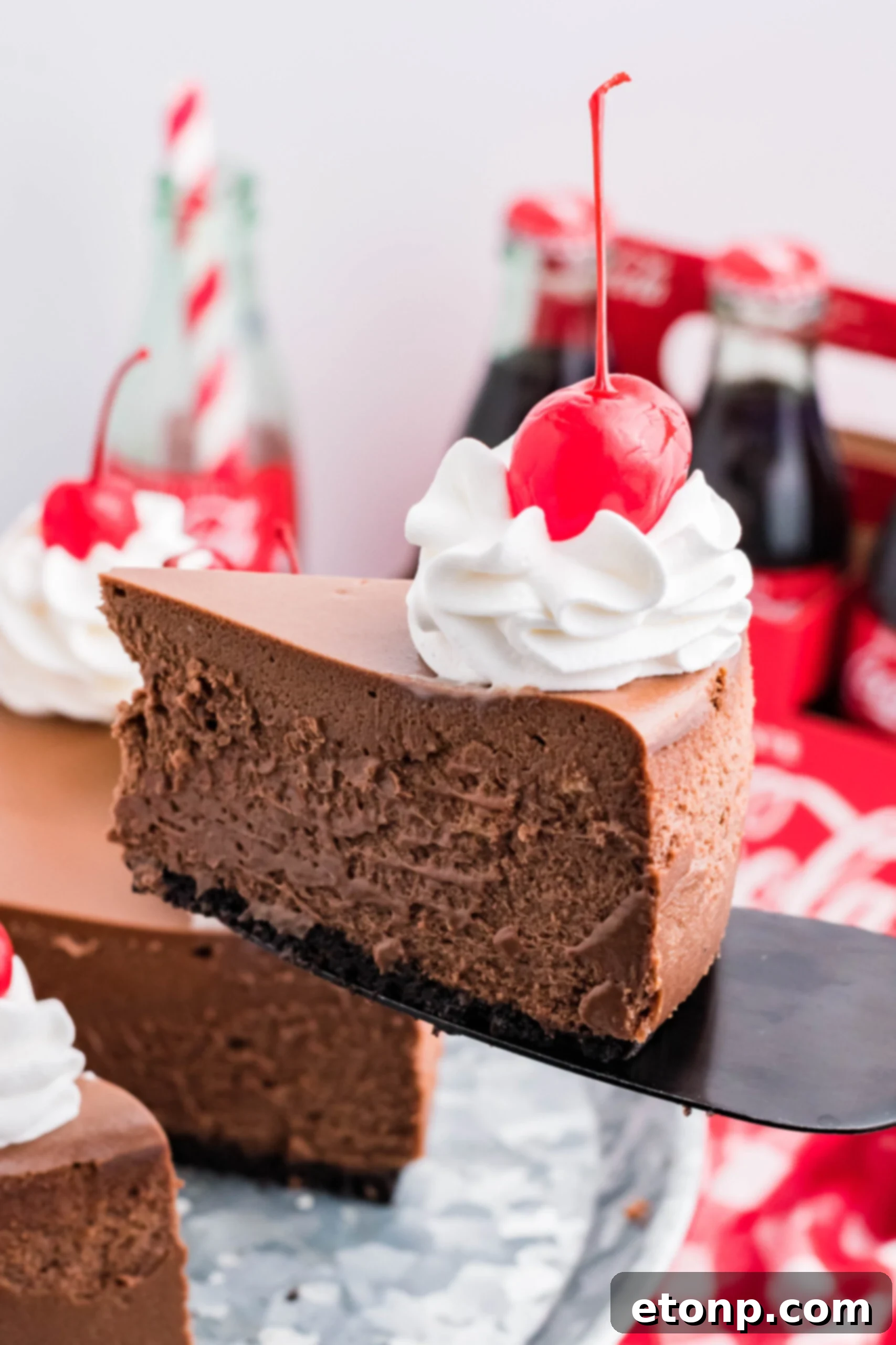 Decadent Coca-Cola Cheesecake 2 Side view of a slice of Coca Cola Cheesecake on a black cake server.