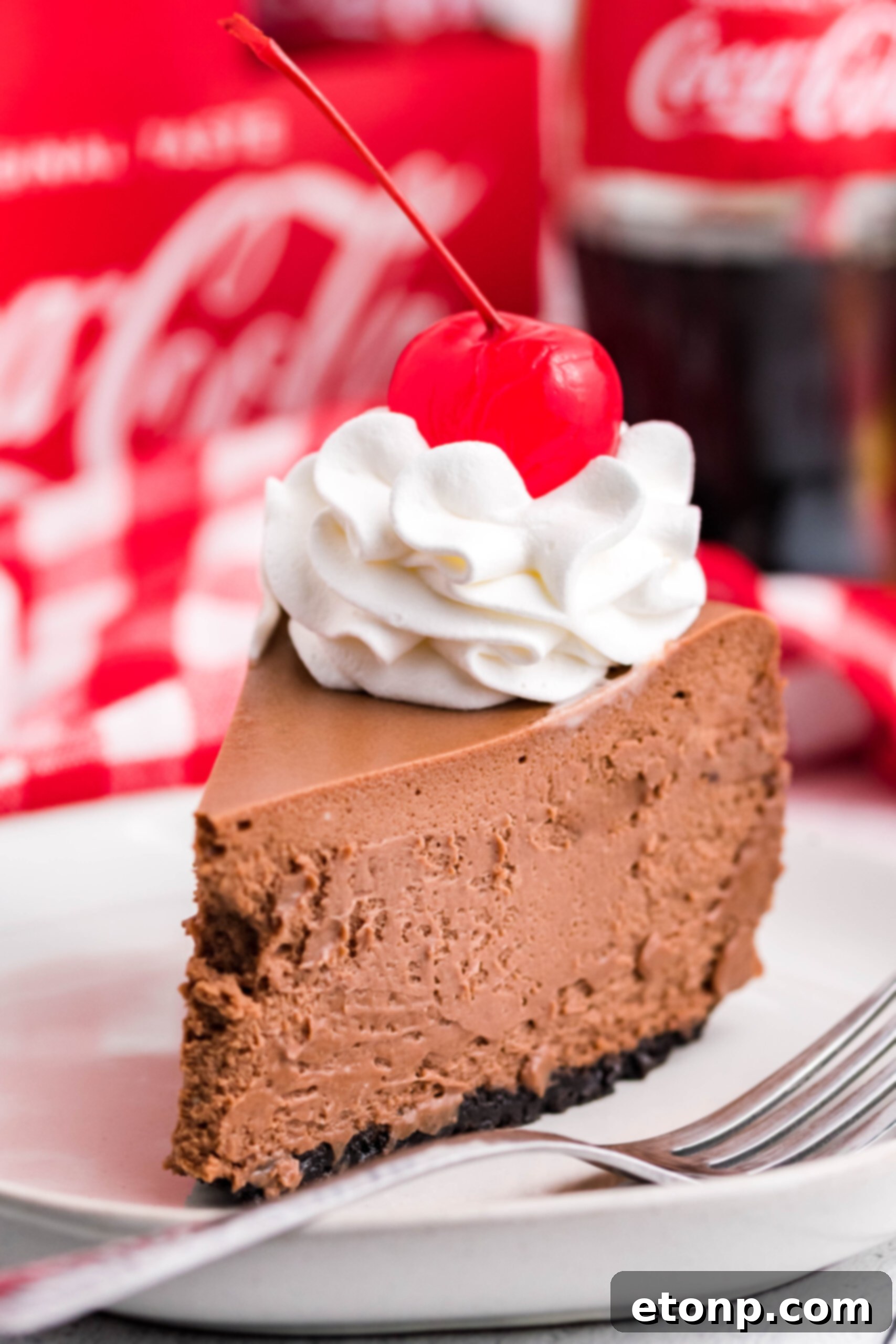Decadent Coca-Cola Cheesecake 7 Side view of a slice of Coca Cola on a white dish.
