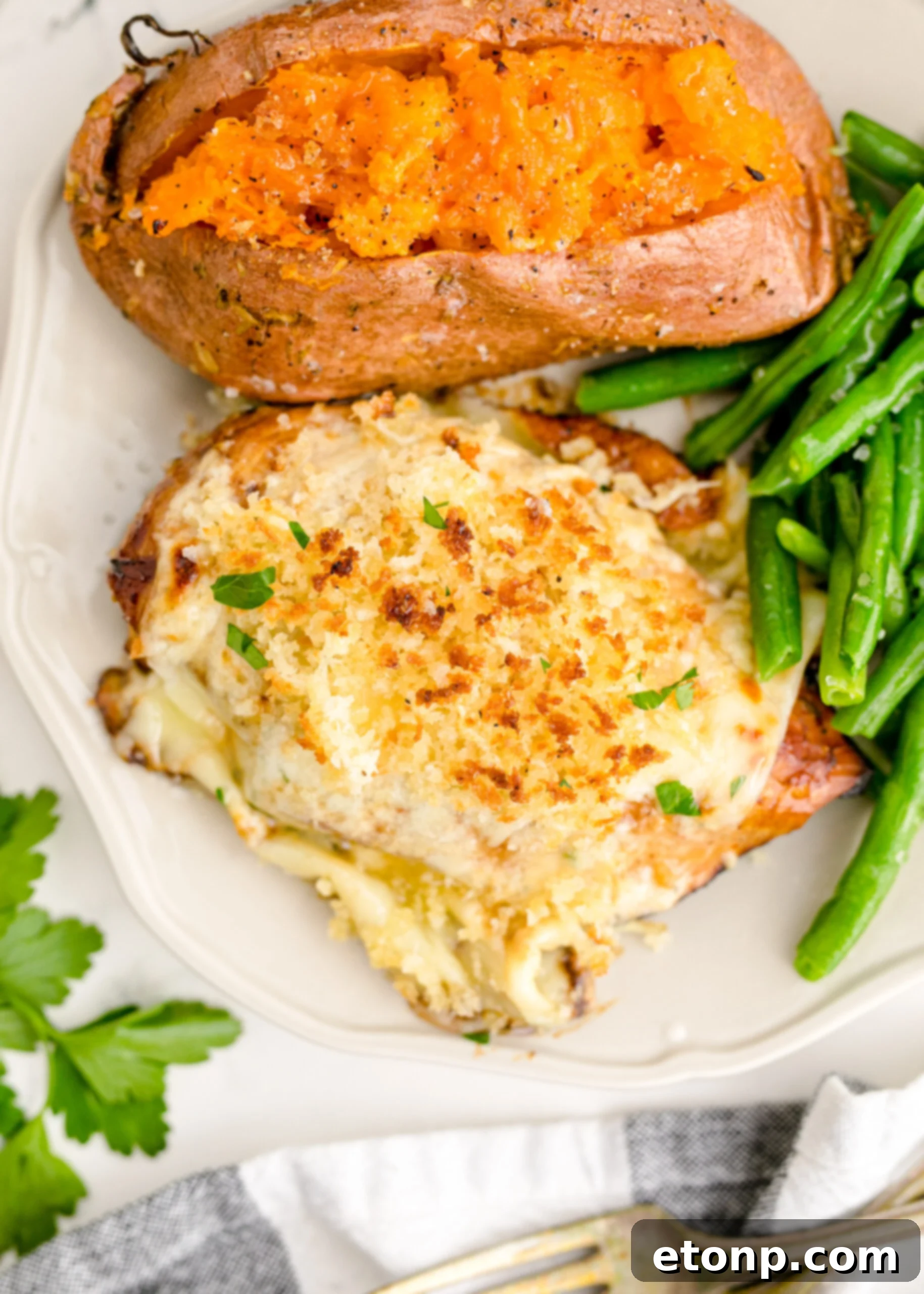Crispy Parmesan Chicken 4 Up close view of Parmesan Crusted Chicken (Longhorn Copycat) on a white dish served with vibrant green beans and a perfectly baked sweet potato.
