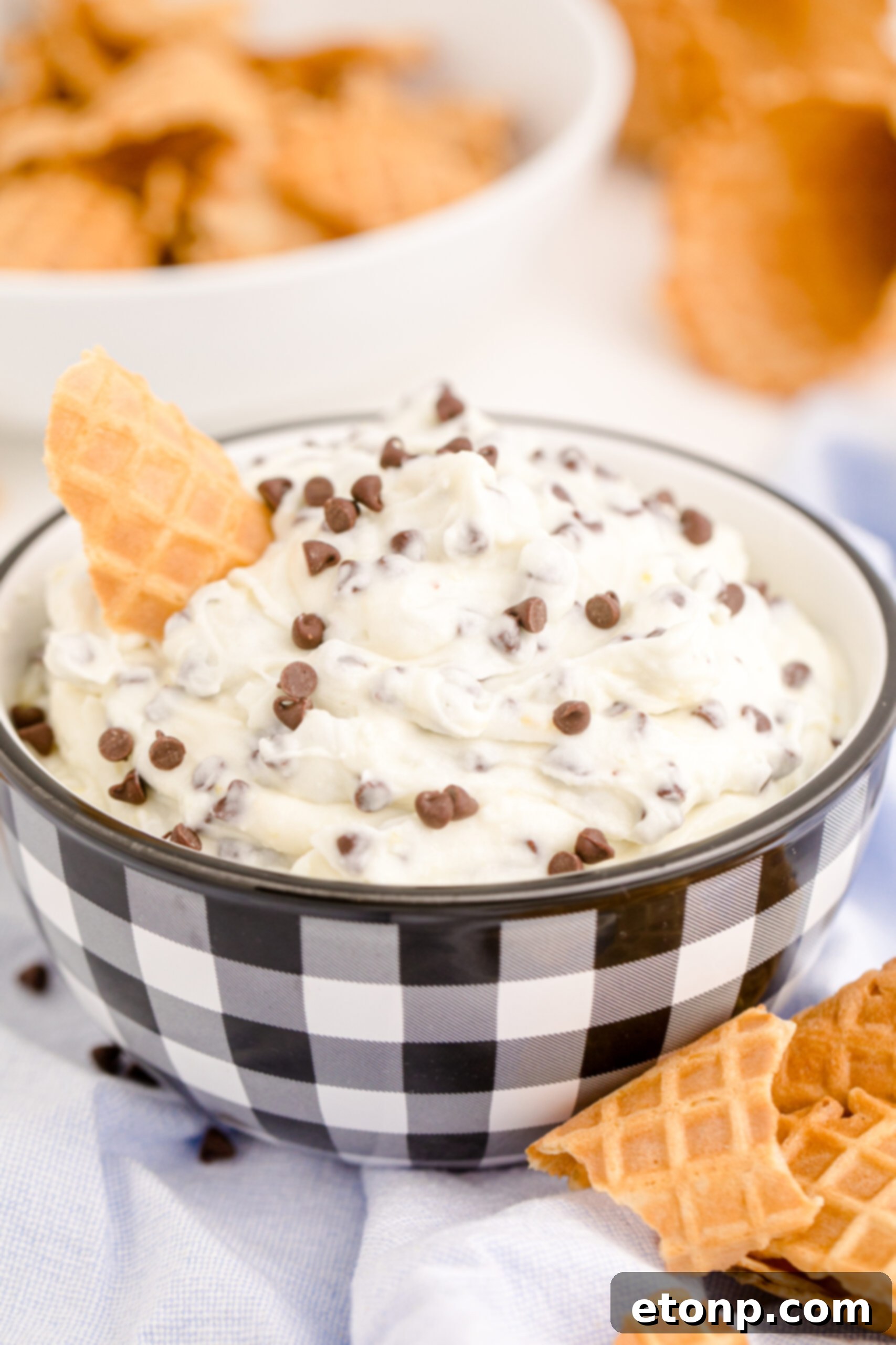 Another beautiful side view of the Cannoli Dip in a decorative black and white bowl, with a golden waffle cone ready for dipping.