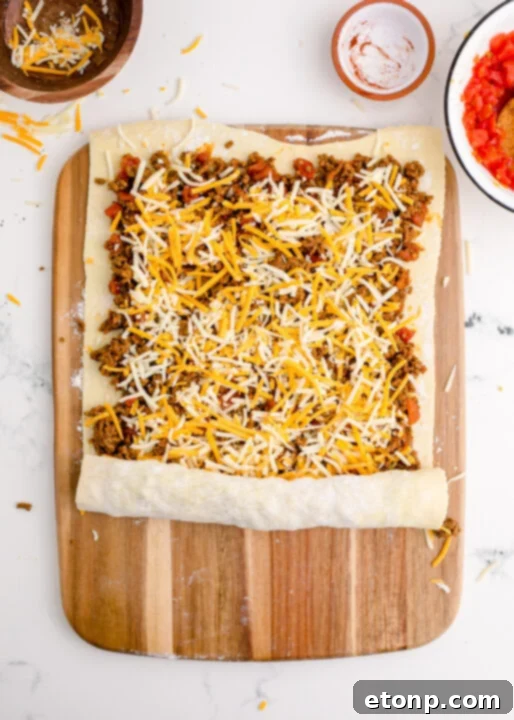 A close-up of a perfectly baked Taco Pinwheel, showing its flaky crust and savory filling, with a hint of melted cheese.