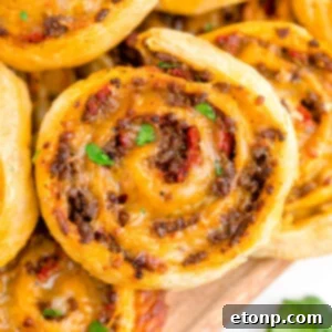 A perfectly baked taco pinwheel with a golden crust and visible filling, presented as the main image for the recipe card.