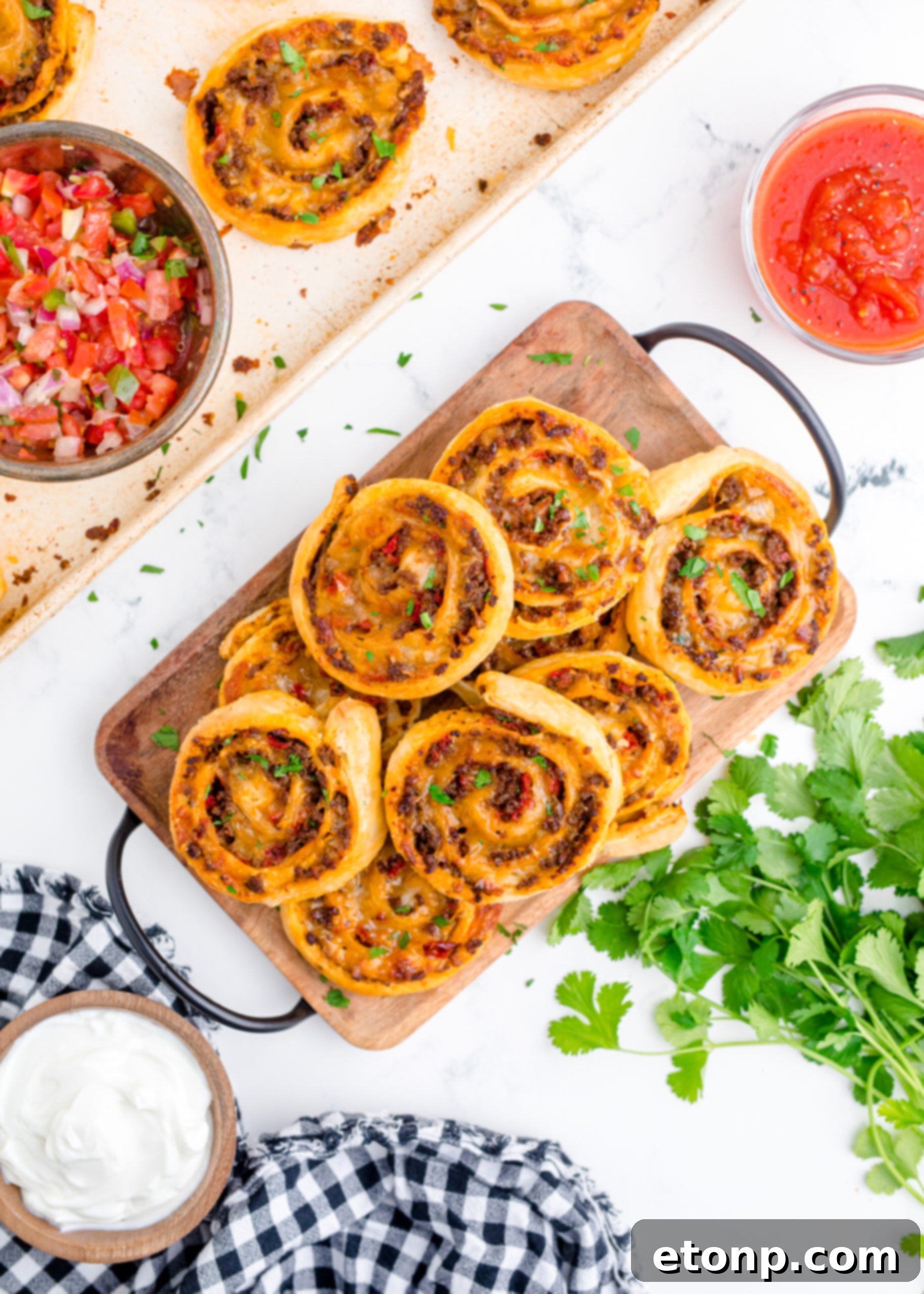 Overhead shot of freshly baked Taco Pinwheels arranged artfully on a wooden cutting board, highlighting their spiraled appearance.
