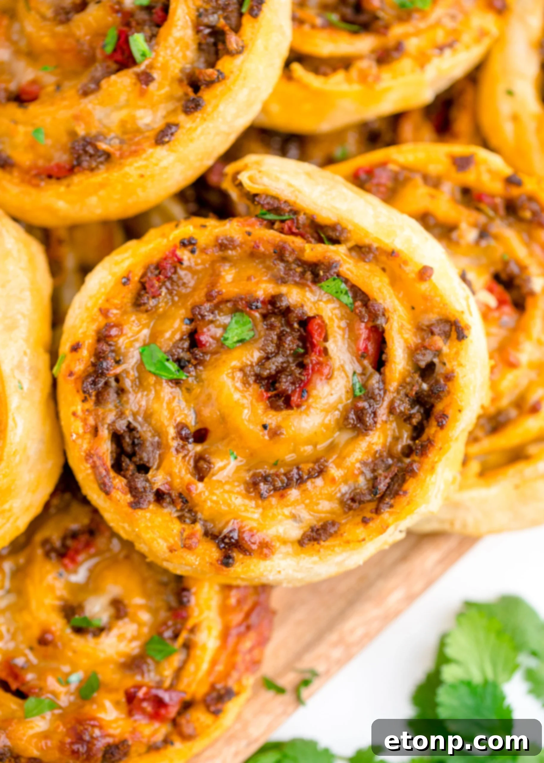 A close-up photograph of several Taco Pinwheels artfully arranged on a wooden board, ready for serving.
