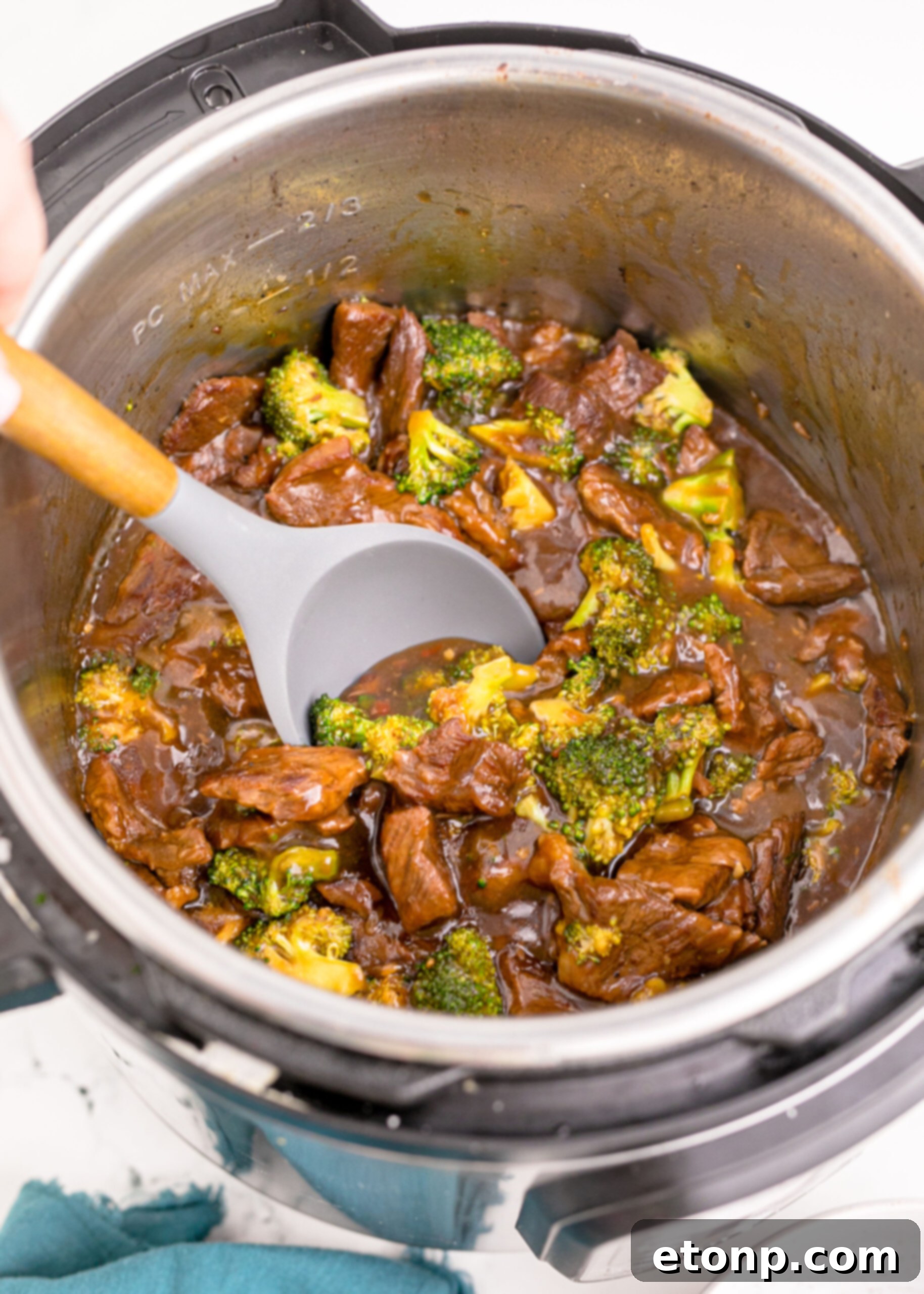 Close-up view of Instant Pot Beef and Broccoli served in a bowl, with a spoon lifting a piece of beef and broccoli, showcasing its delicious texture.