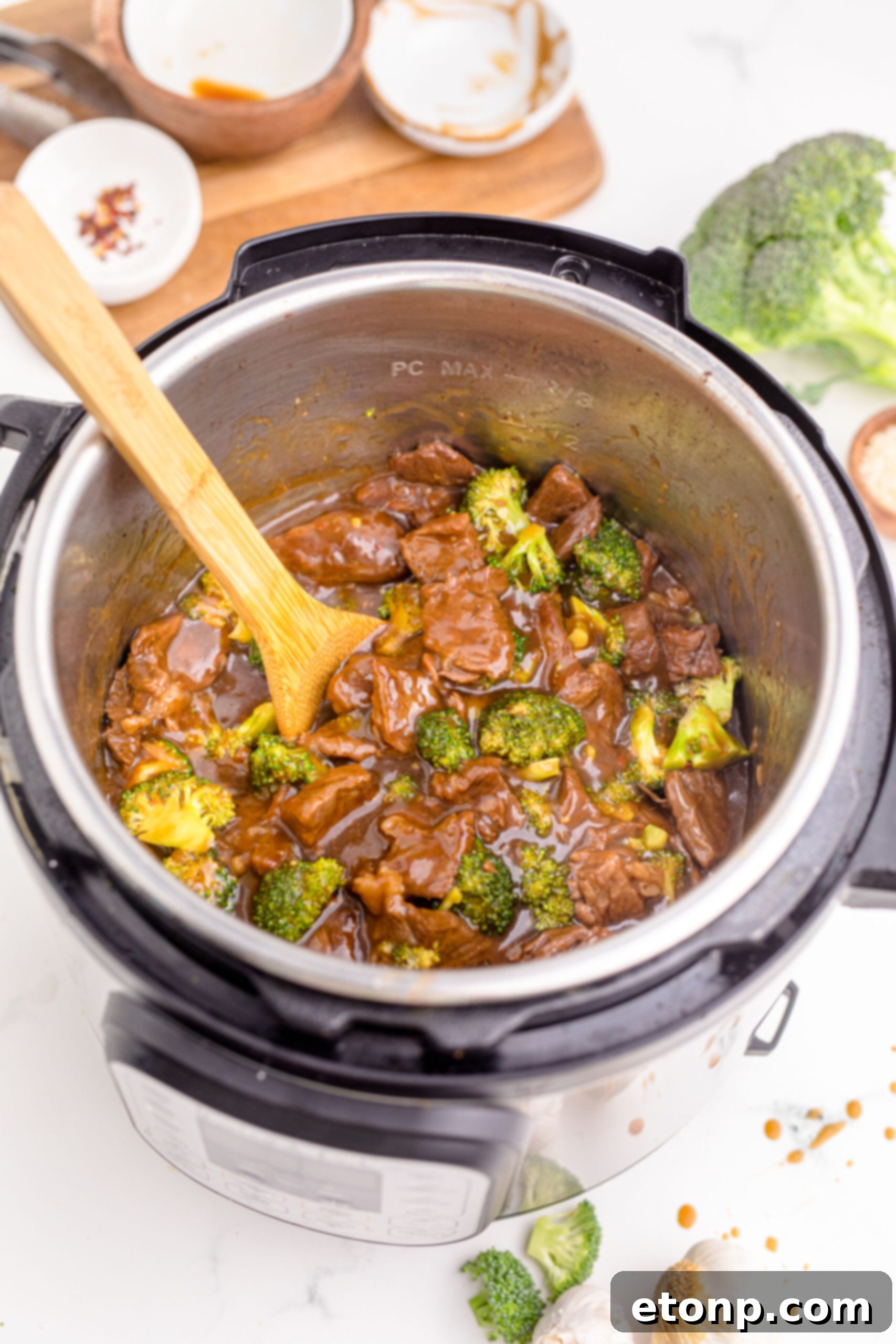 Instant Pot Beef and Broccoli steaming inside the Instant Pot, with a wooden spoon stirring the delicious contents, highlighting its readiness.