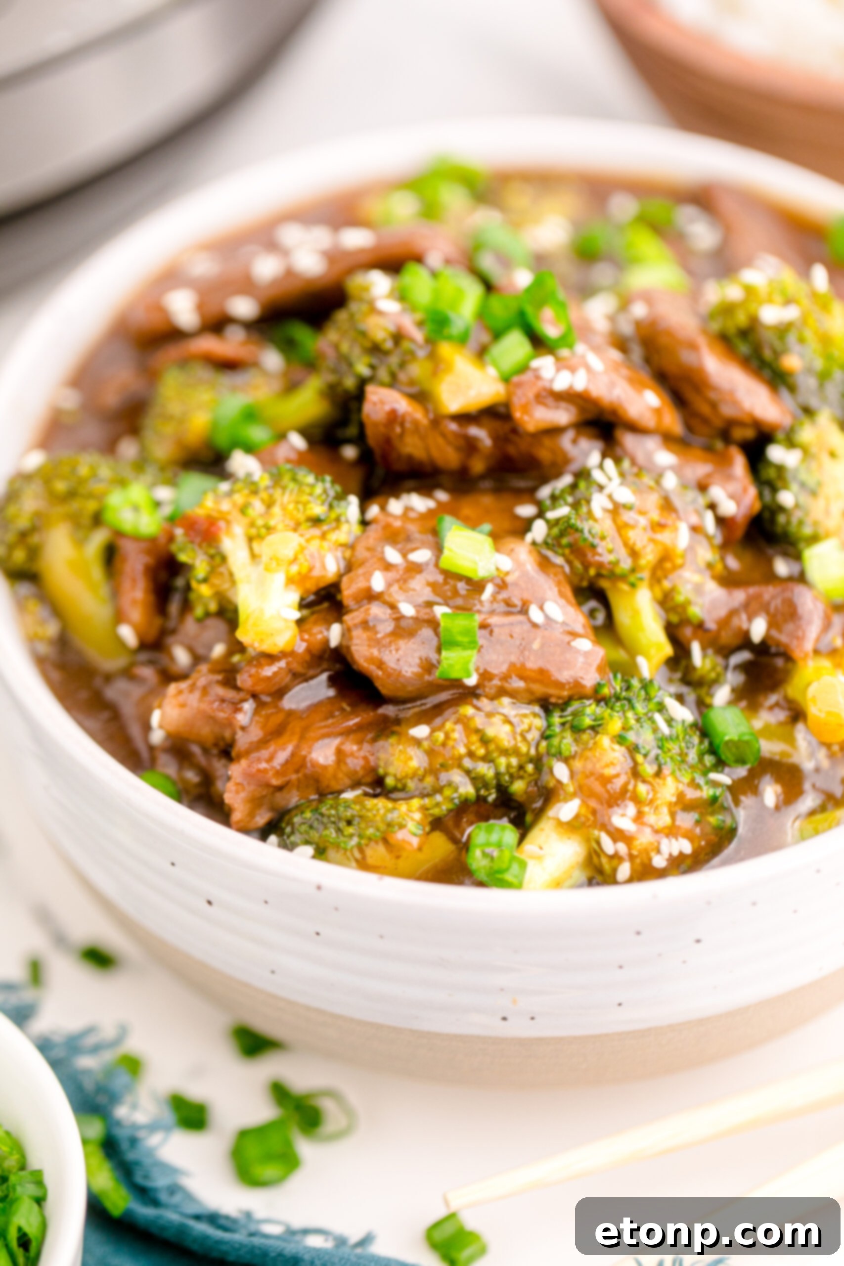 Up-close, detailed view of Instant Pot Beef and Broccoli presented in a stylish white and tan bowl, emphasizing the tender beef and vibrant broccoli.
