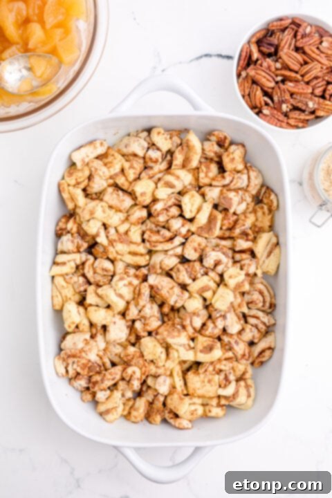 Cinnamon roll pieces arranged in a baking dish, covered with melted butter.