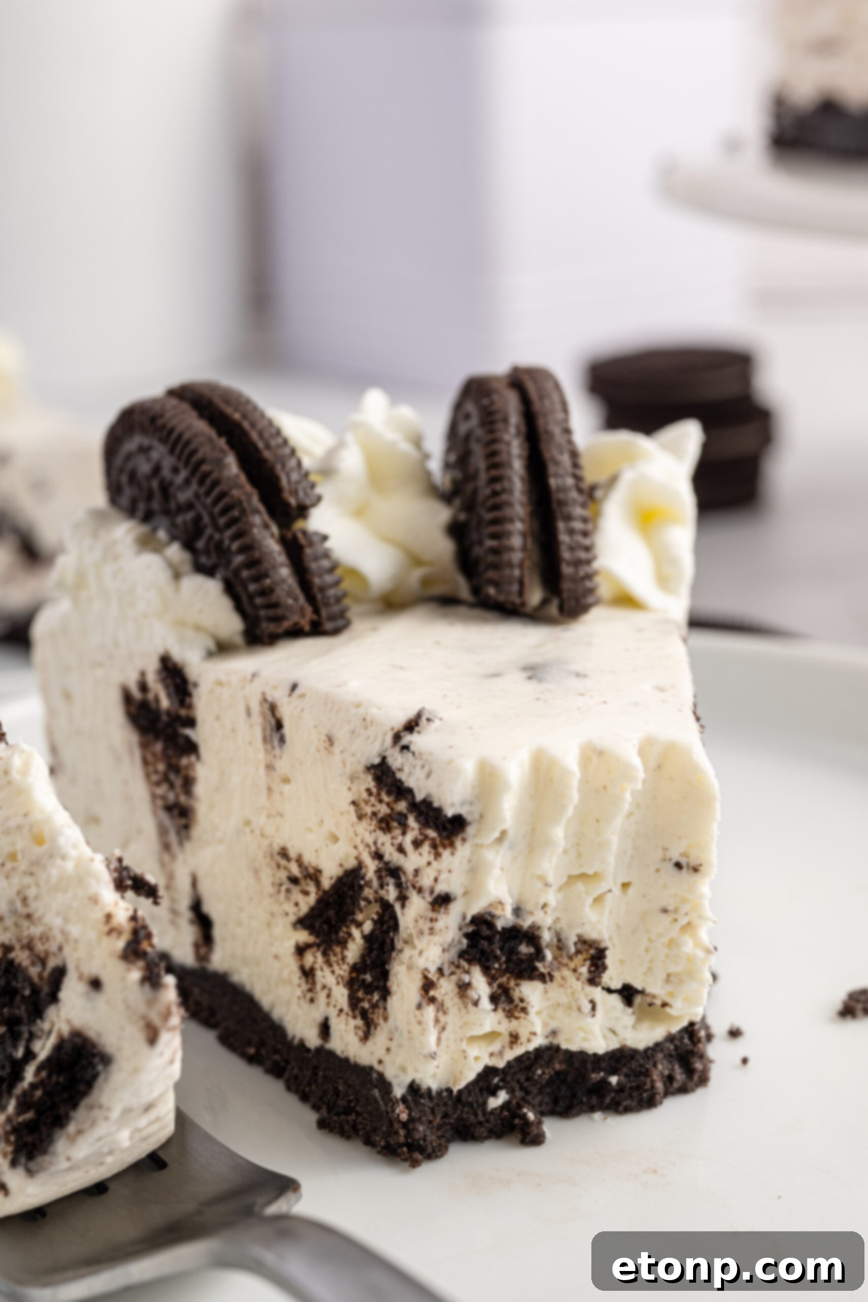 No-Bake Oreo Cheesecake Magic 14 Up close and inviting view of a slice of No Bake Oreo Cheesecake, with a silver fork digging in, emphasizing its smooth, creamy texture.