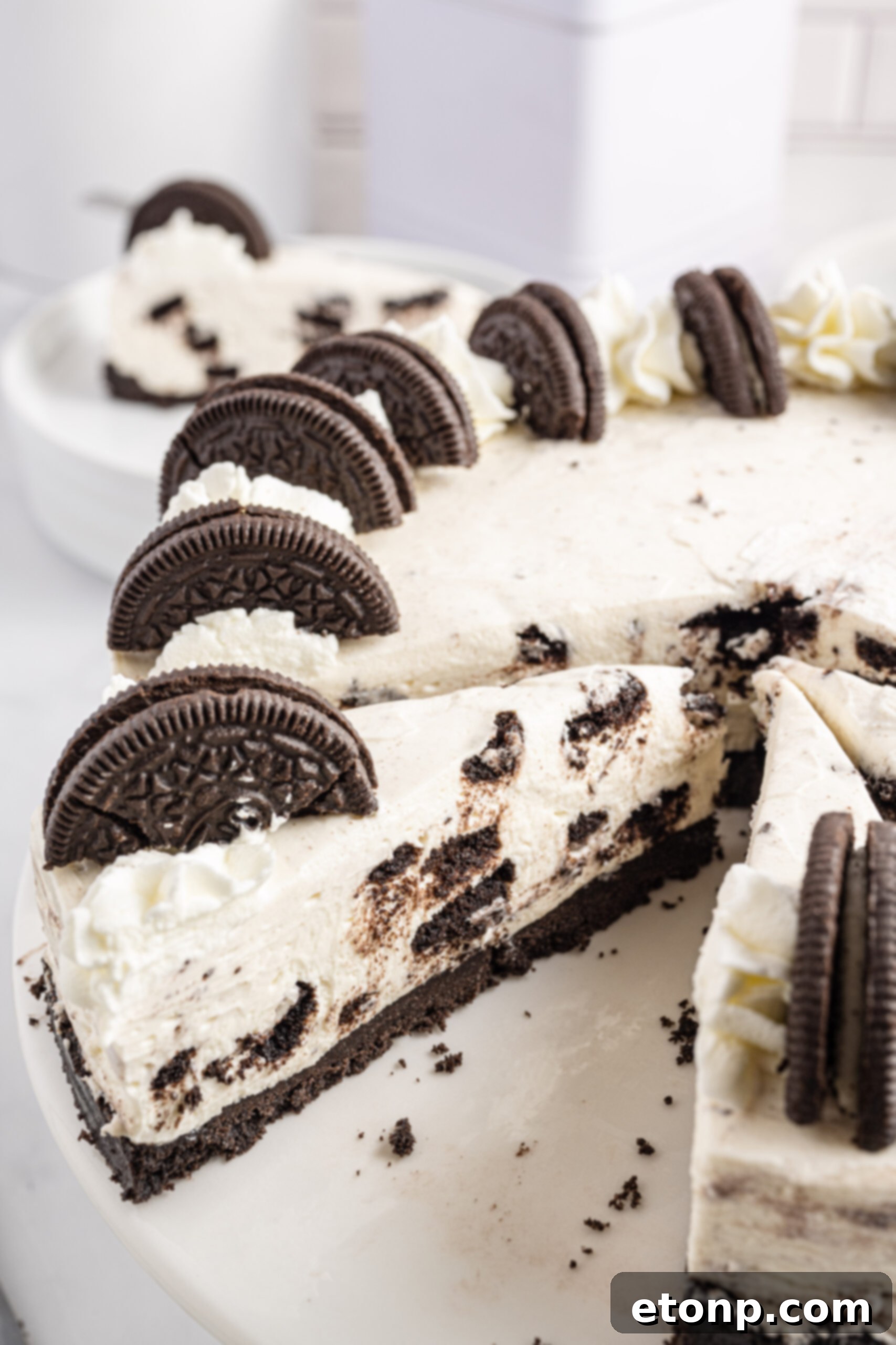 No-Bake Oreo Cheesecake Magic 5 Close-up view of a slice of No Bake Oreo Cheesecake being removed from the pan with a silver fork, highlighting the creamy filling and distinct Oreo layers.