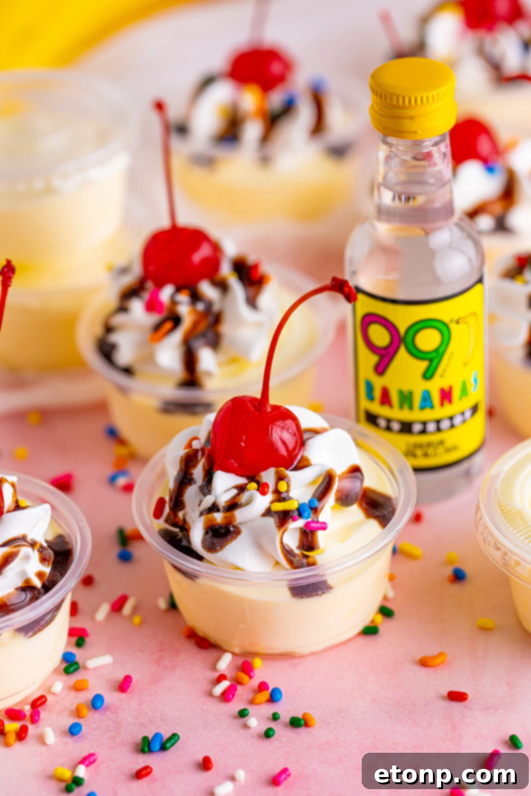 Side view of Banana Split Shots surrounded by rainbow sprinkles.