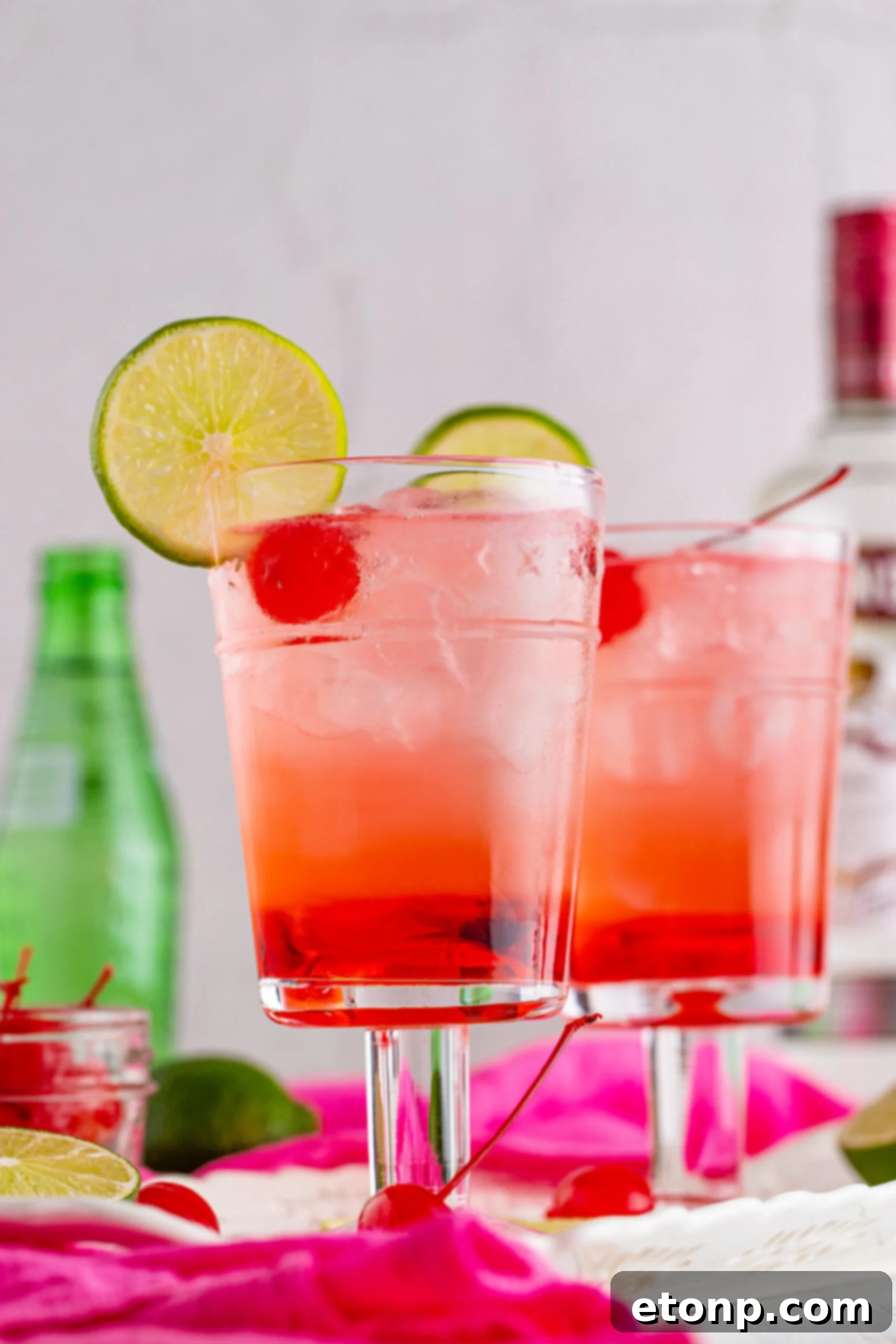 Side view of Dirty Shirley Temple garnished with a lime slice and cherry.
