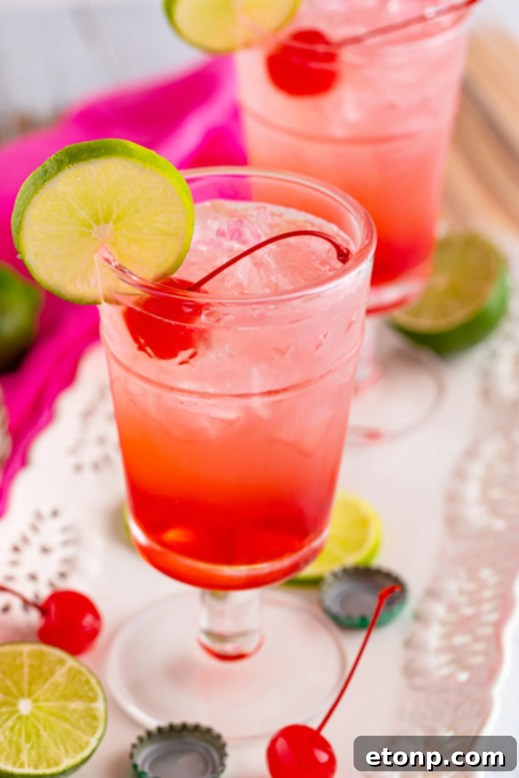 Side view of Dirty Shirley Temple garnished with a lime slice and cherry.