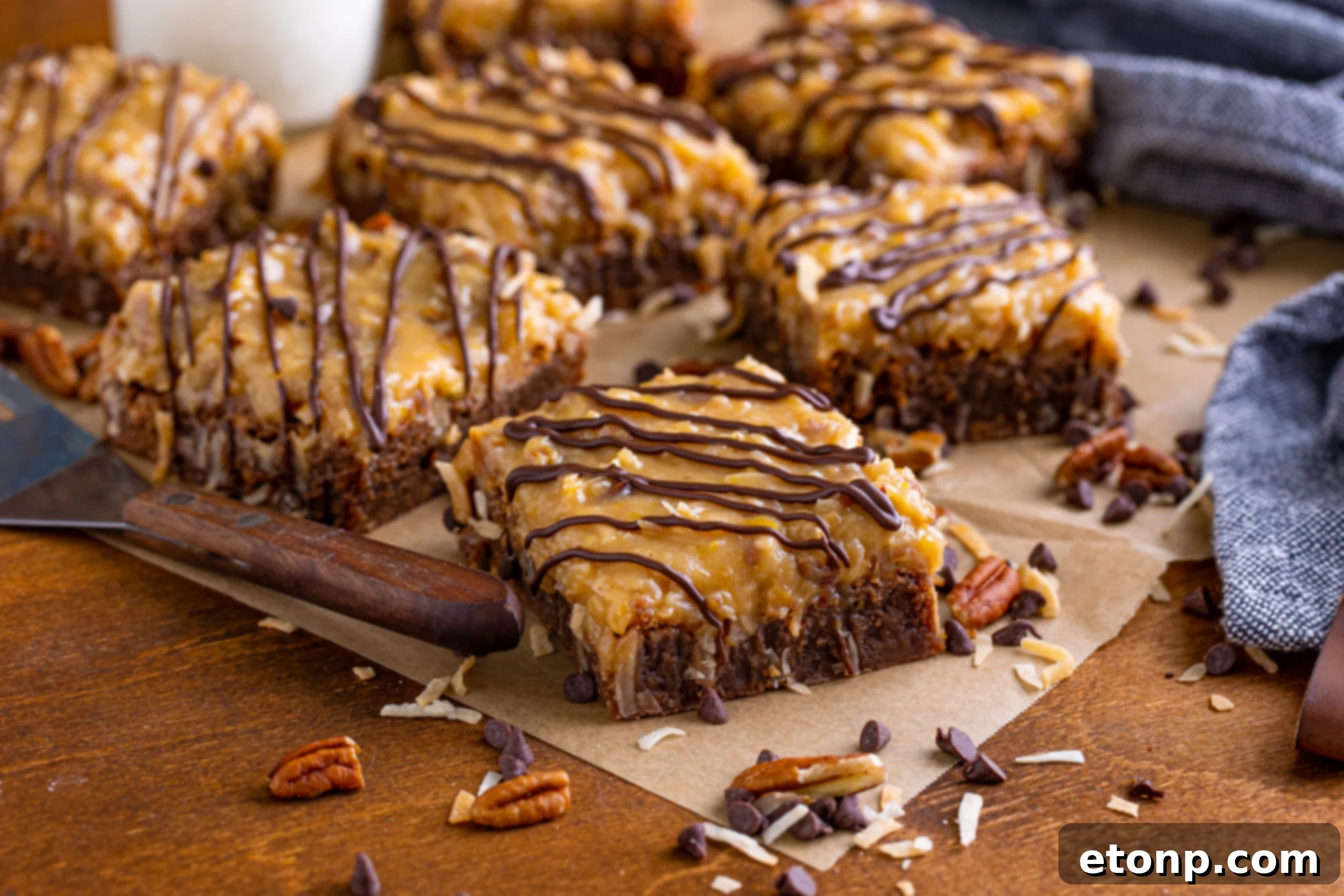 German Chocolate Brownies on a rustic wood table, surrounded by scattered chopped pecans and chocolate chips for a cozy presentation.