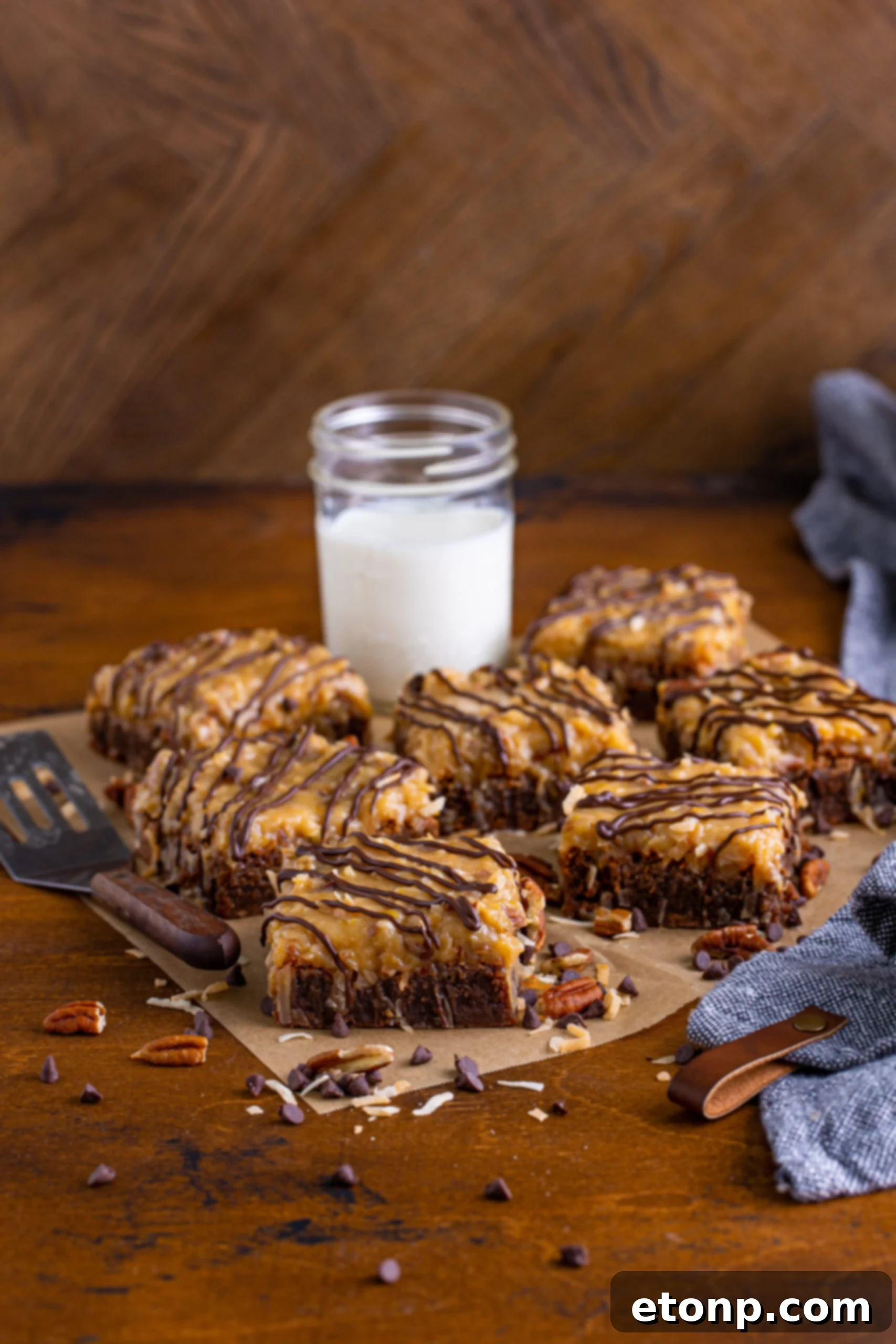 Front view of several German Chocolate Brownies arranged artfully on a piece of parchment paper, highlighting their glossy topping.