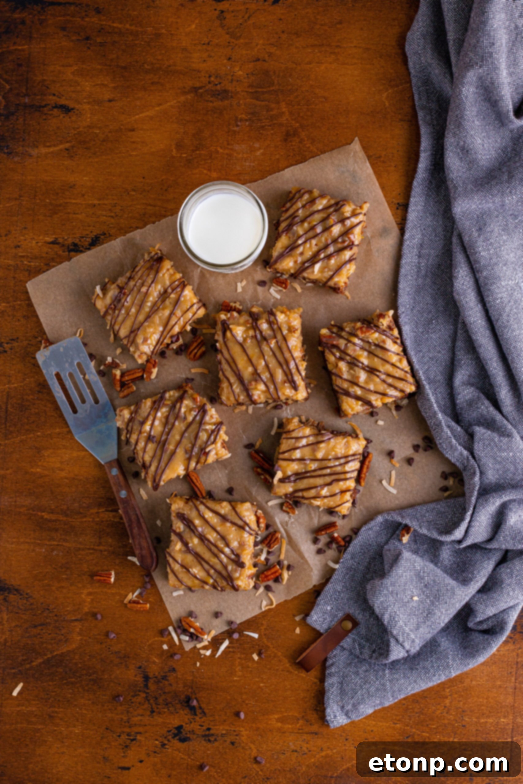Overhead shot of a tray of German Chocolate Brownies on parchment paper, showcasing their even cuts and inviting appearance.
