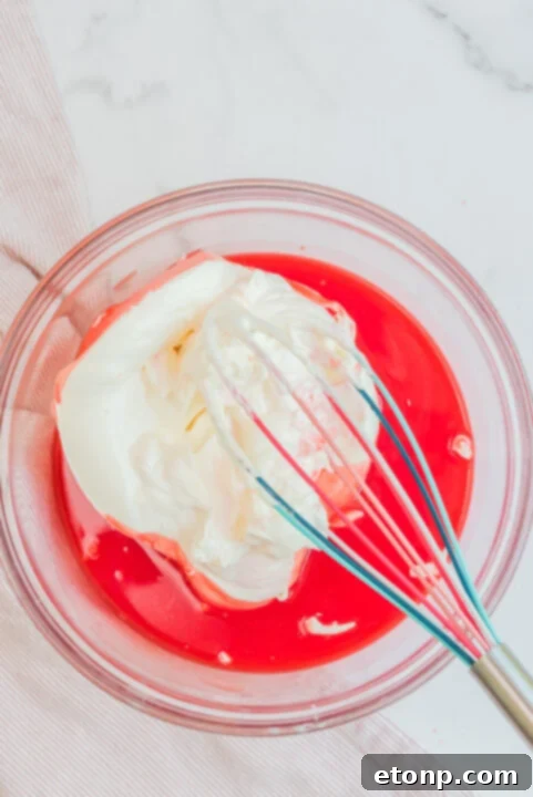 A spoon scooping a portion of Raspberry Jello Fluff from a bowl.