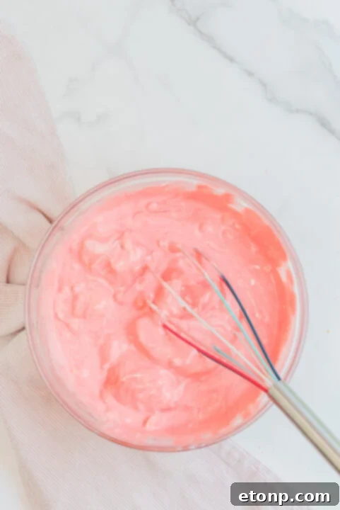 Raspberry Jello Fluff served in a small white ramekin with a berry on top.