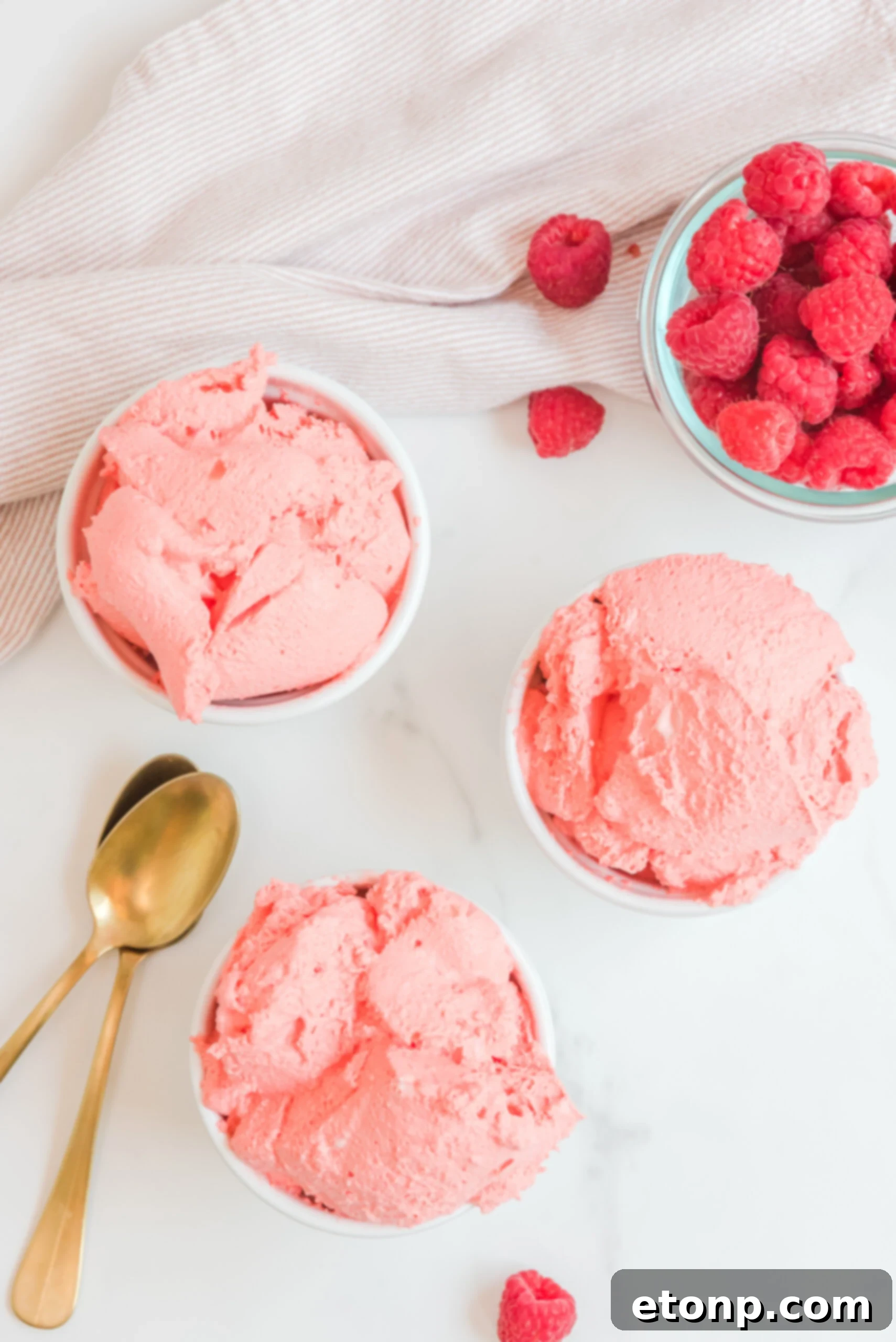 Overhead view of three white dishes containing Raspberry Jello Fluff, demonstrating a serving size and the dessert's uniform texture before garnishing.