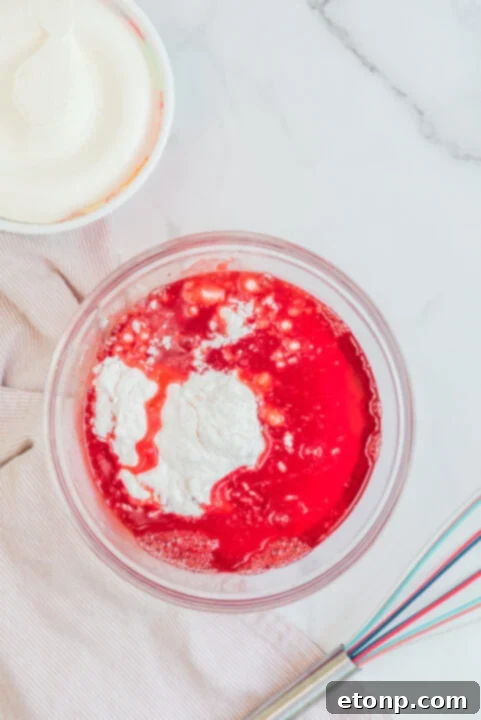 Raspberry Jello Fluff in a clear glass bowl, showcasing its layered texture.