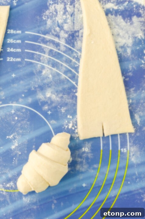 Croissant dough being rolled into crescent shape