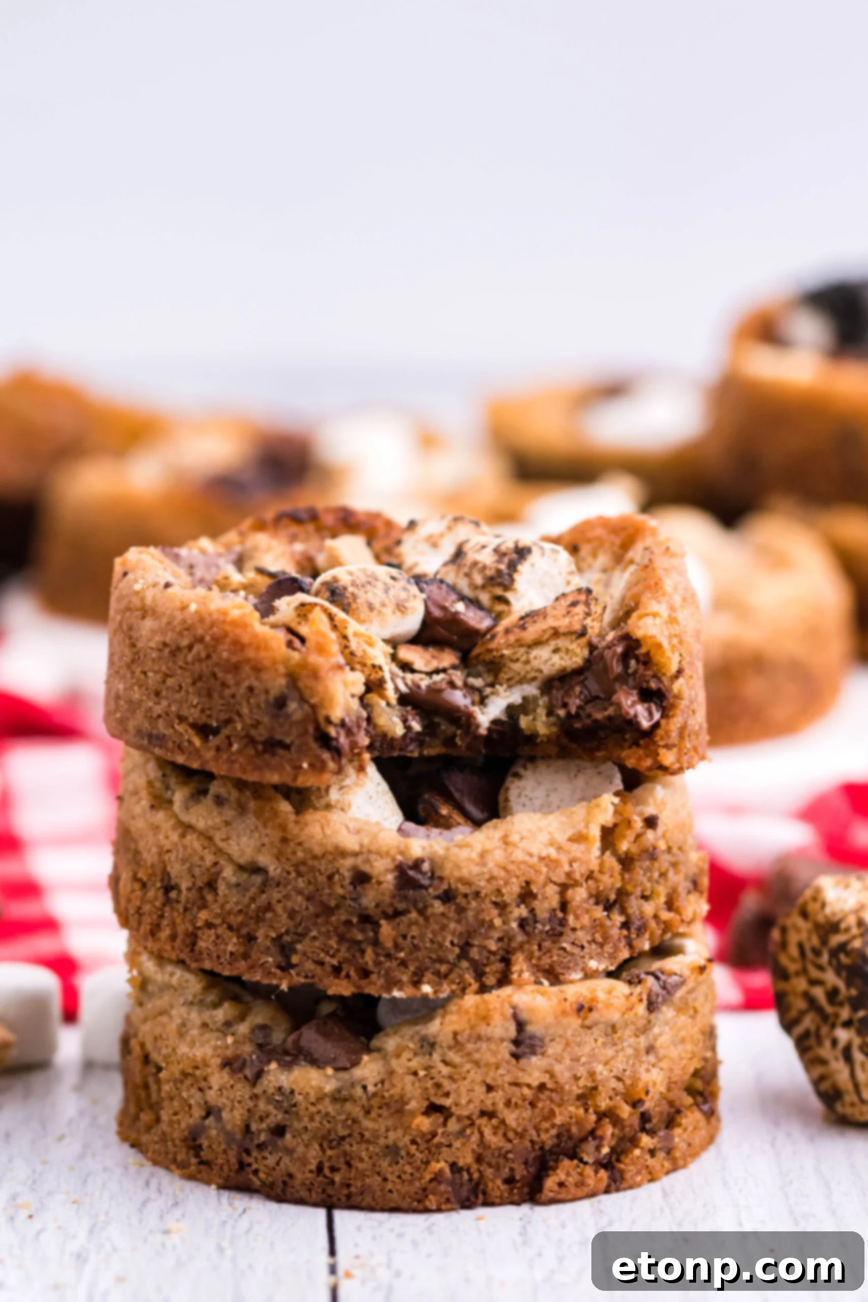 Front view of three Deep Dish S’mores Cookies staked with a bite removed from the top cookie.