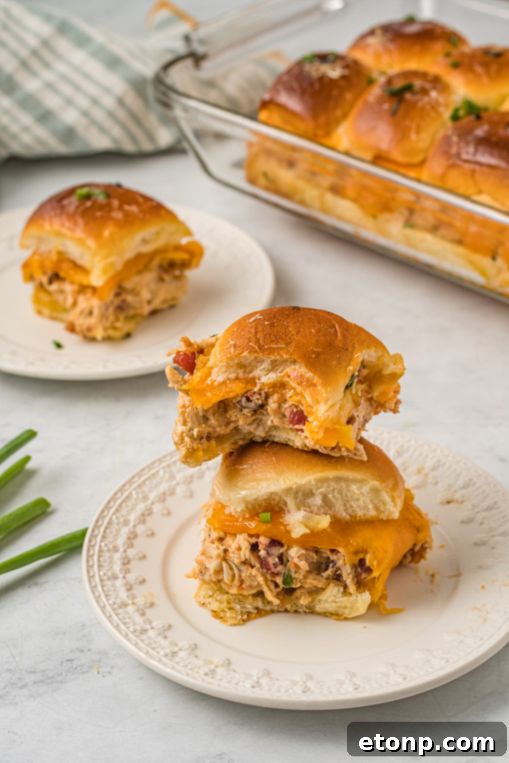 Front view of two Crack Chicken Sliders
stacked on a white plate with a bite removed from the top slider. 