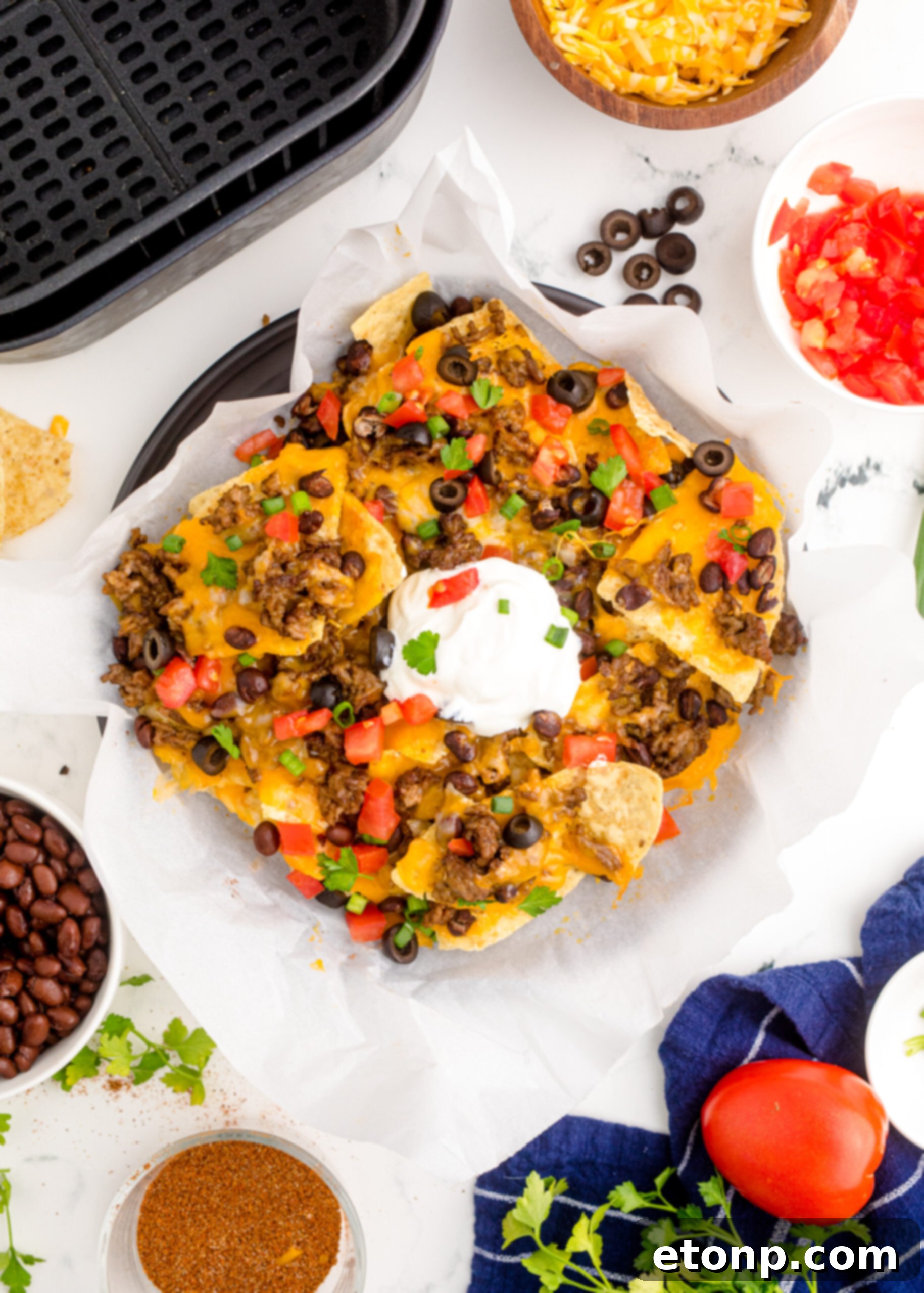 Overhead view of Air Fryer Nachos in an black dish with parchment paper.