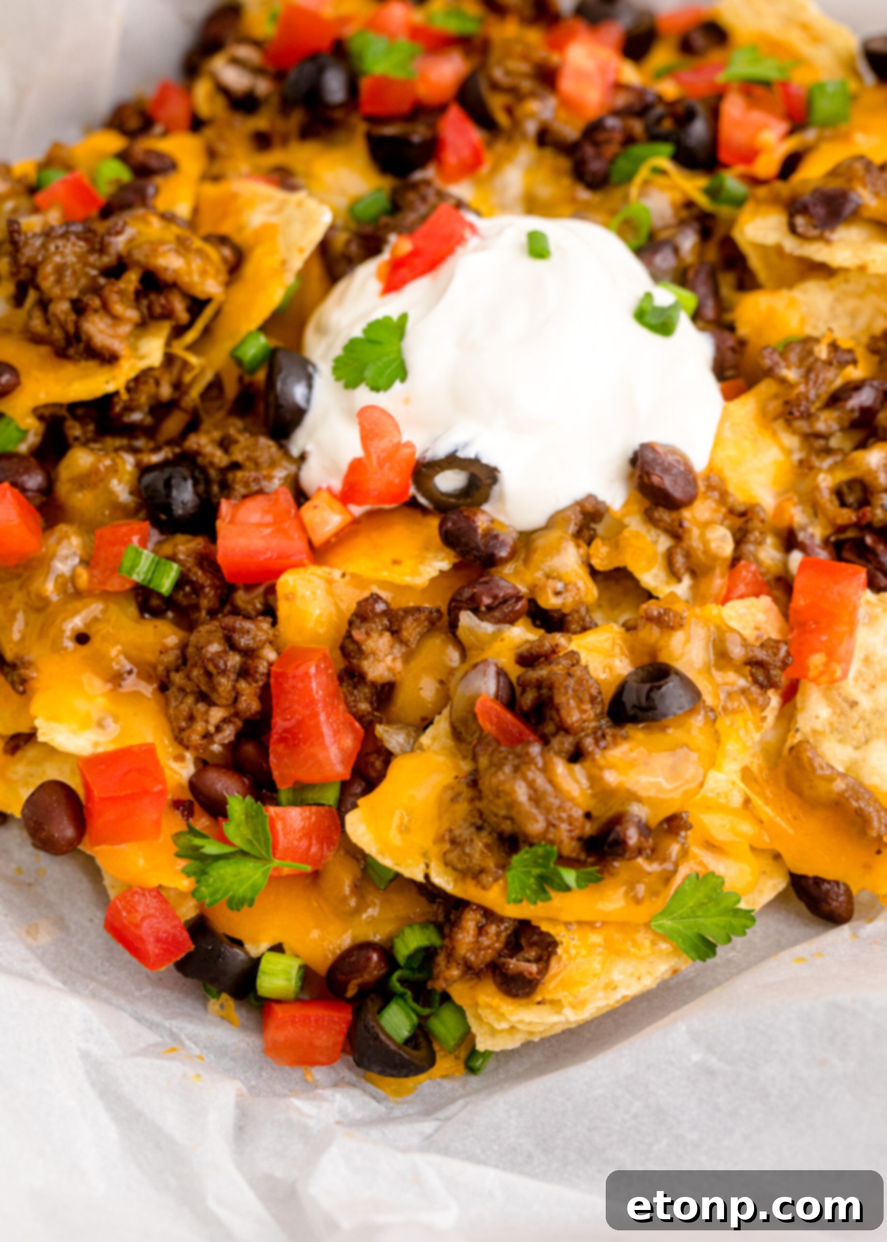 Close up view of Air Fryer Nachos in an black dish with parchment paper.