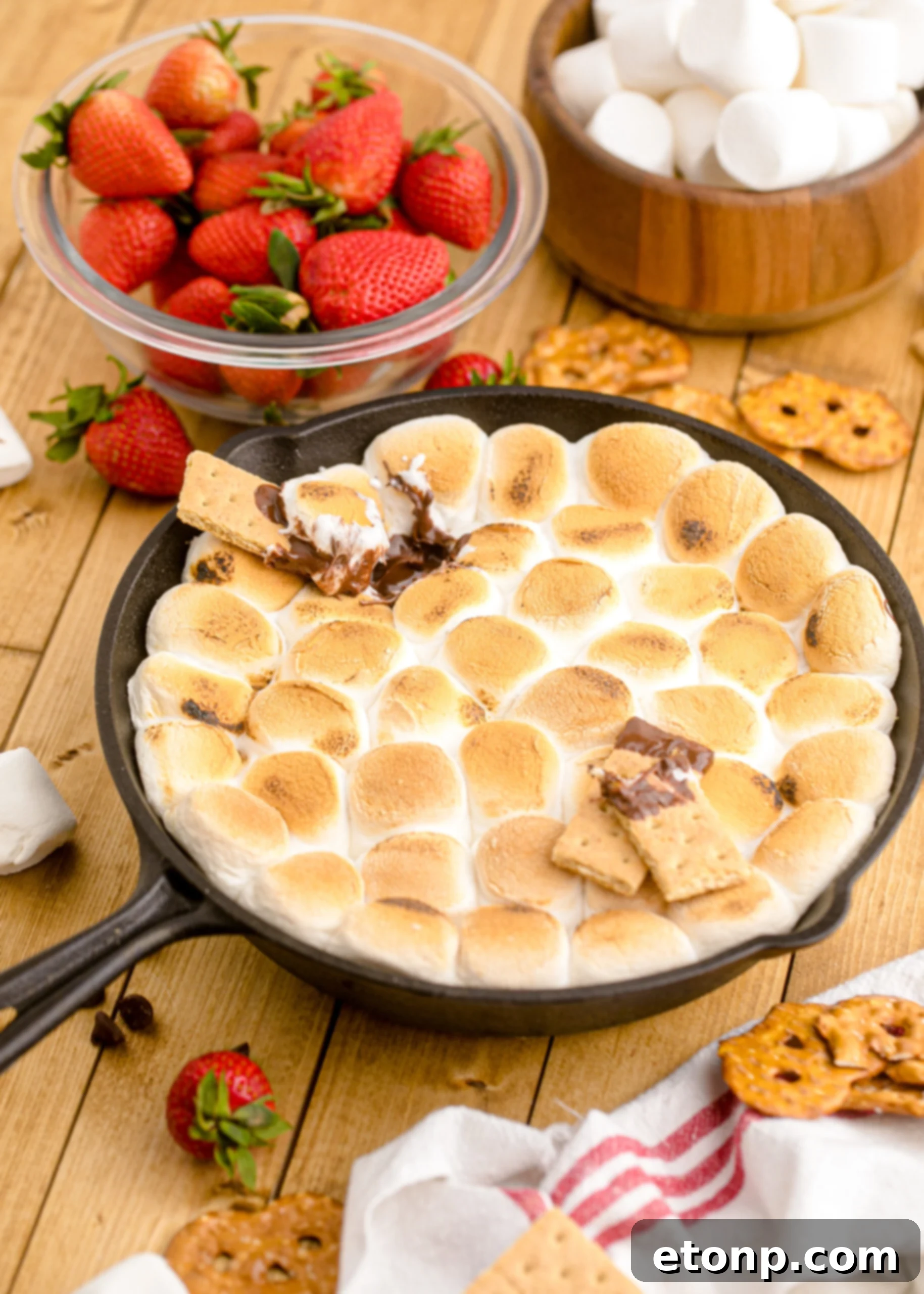 A front-angle shot of S'mores Dip in a cast iron skillet, adorned with graham crackers strategically placed on top for easy dipping.