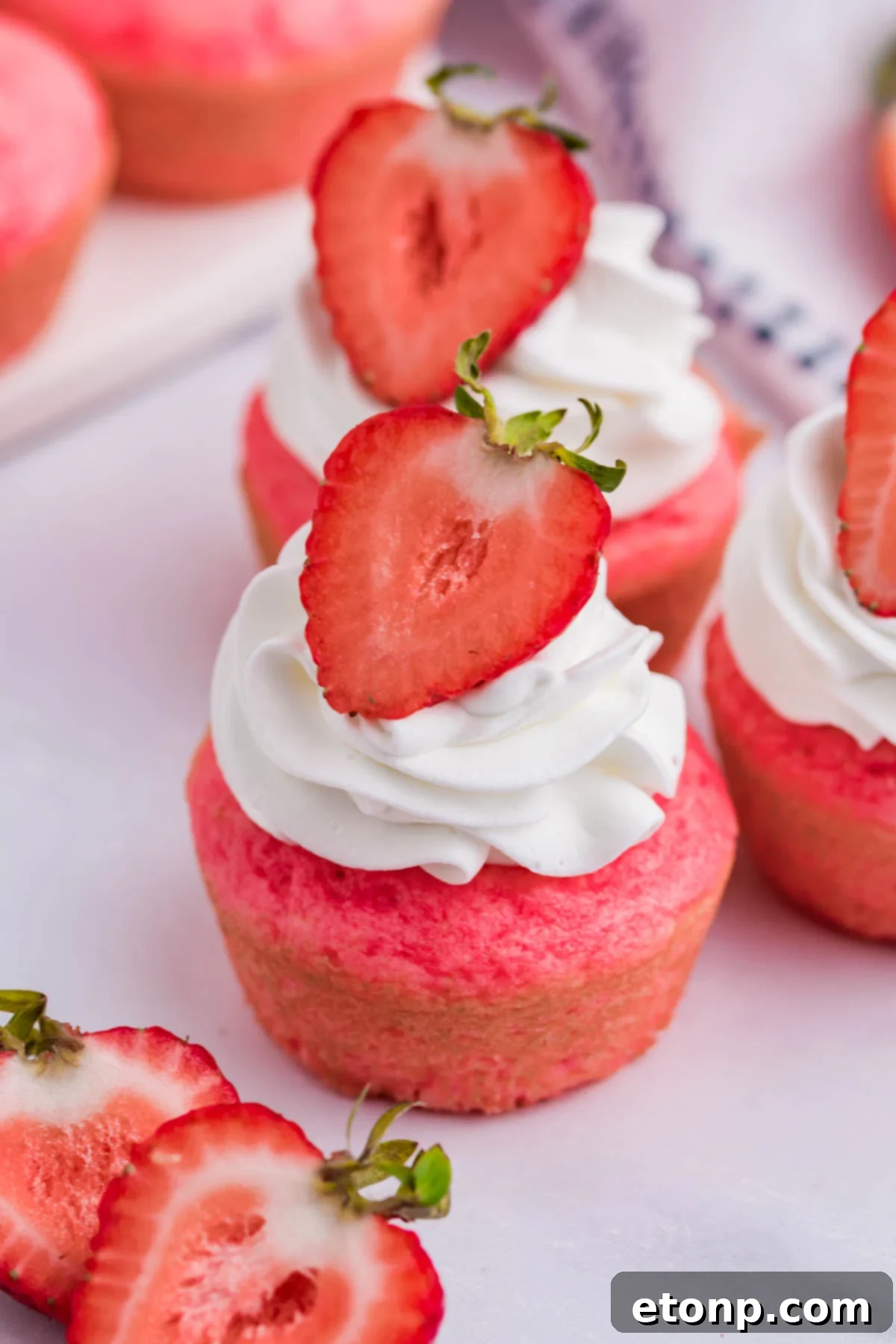 A close-up of a single, beautifully plated Weight Watchers Strawberry Muffin, elegantly topped with whipped cream and a fresh strawberry half, ready to be served.