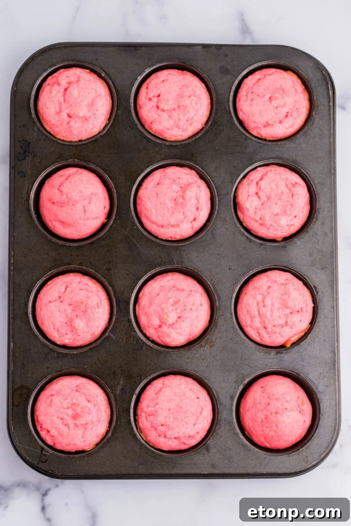 A top-down view of freshly baked Weight Watchers Strawberry Muffins cooling directly in a non-stick muffin pan, ready to be enjoyed.