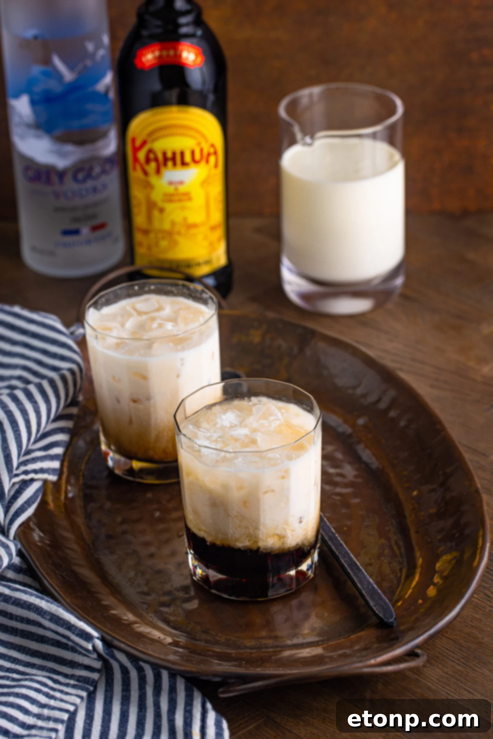 White Russian in a clear glass sitting on a dark metal serving tray, showcasing its elegant simplicity.