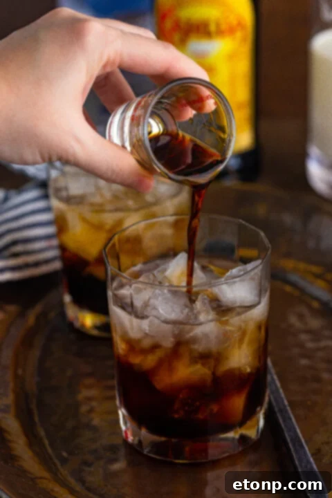 White Russian cocktail, half-filled with the dark base, awaiting the addition of cream.