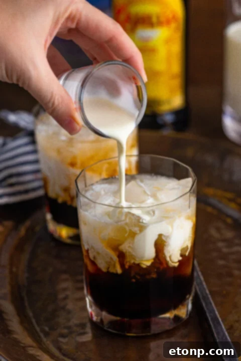 White Russian cocktail with cream being poured on top, creating a beautiful layered effect.