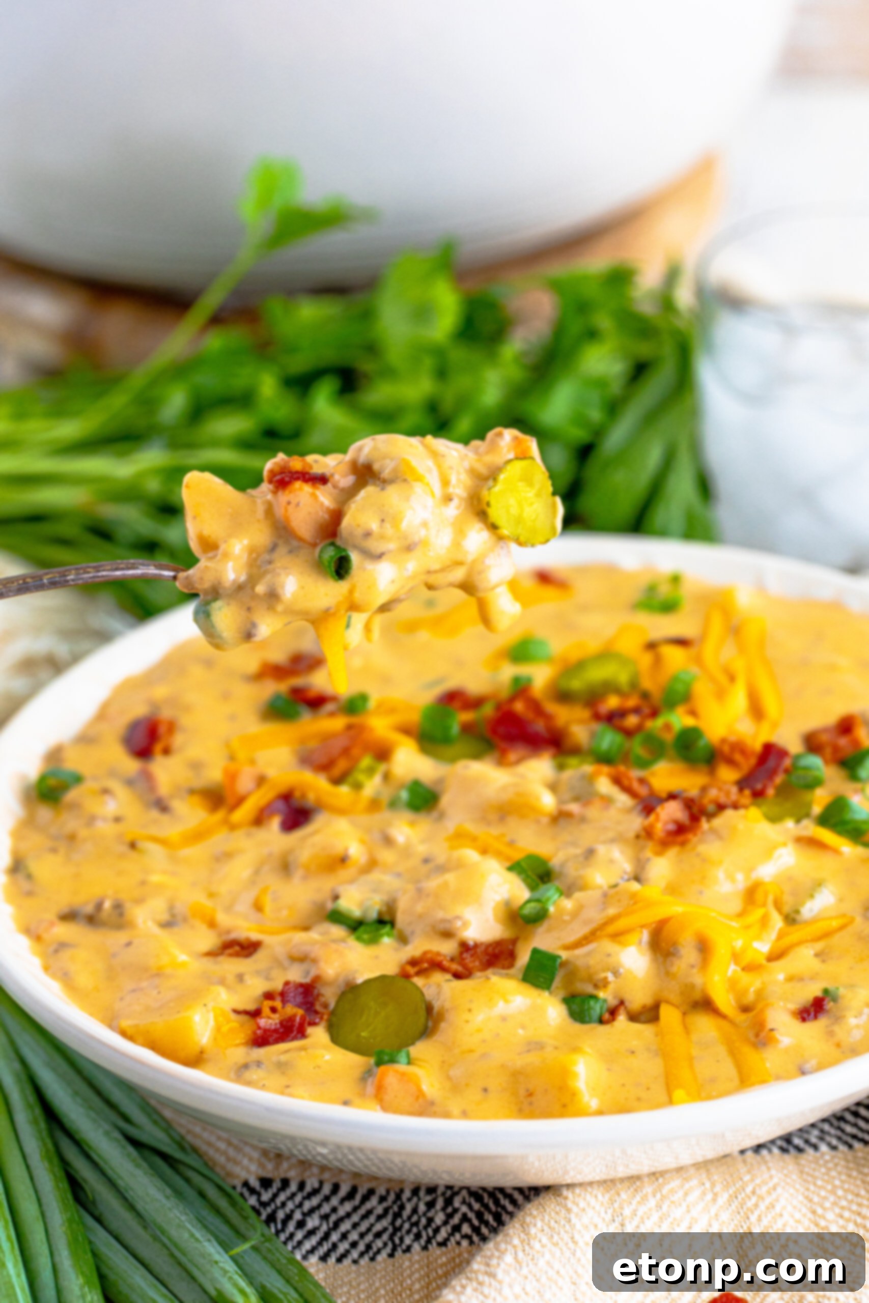 Bacon Cheeseburger Bliss in a Bowl 16 Cheeseburger bacon soup in a white bowl with a silver spoon removing a bite.