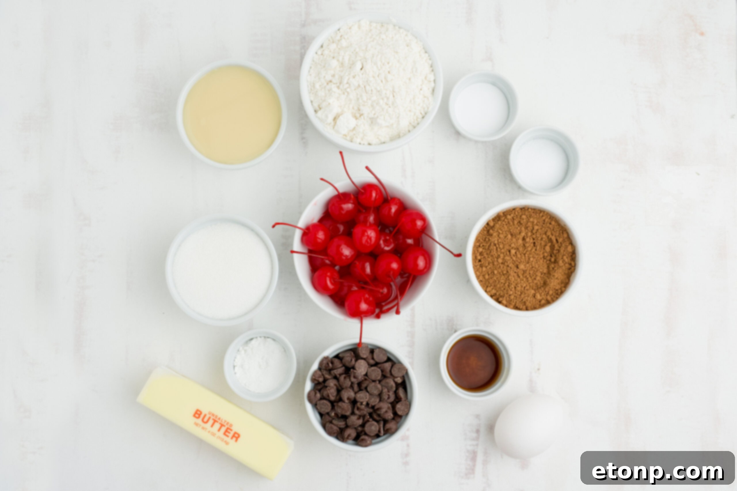 An inviting overhead view showcasing all the fresh, high-quality ingredients meticulously laid out for baking Chocolate Cherry Cookies, including flour, cocoa, butter, sugar, eggs, vanilla, and vibrant maraschino cherries.
