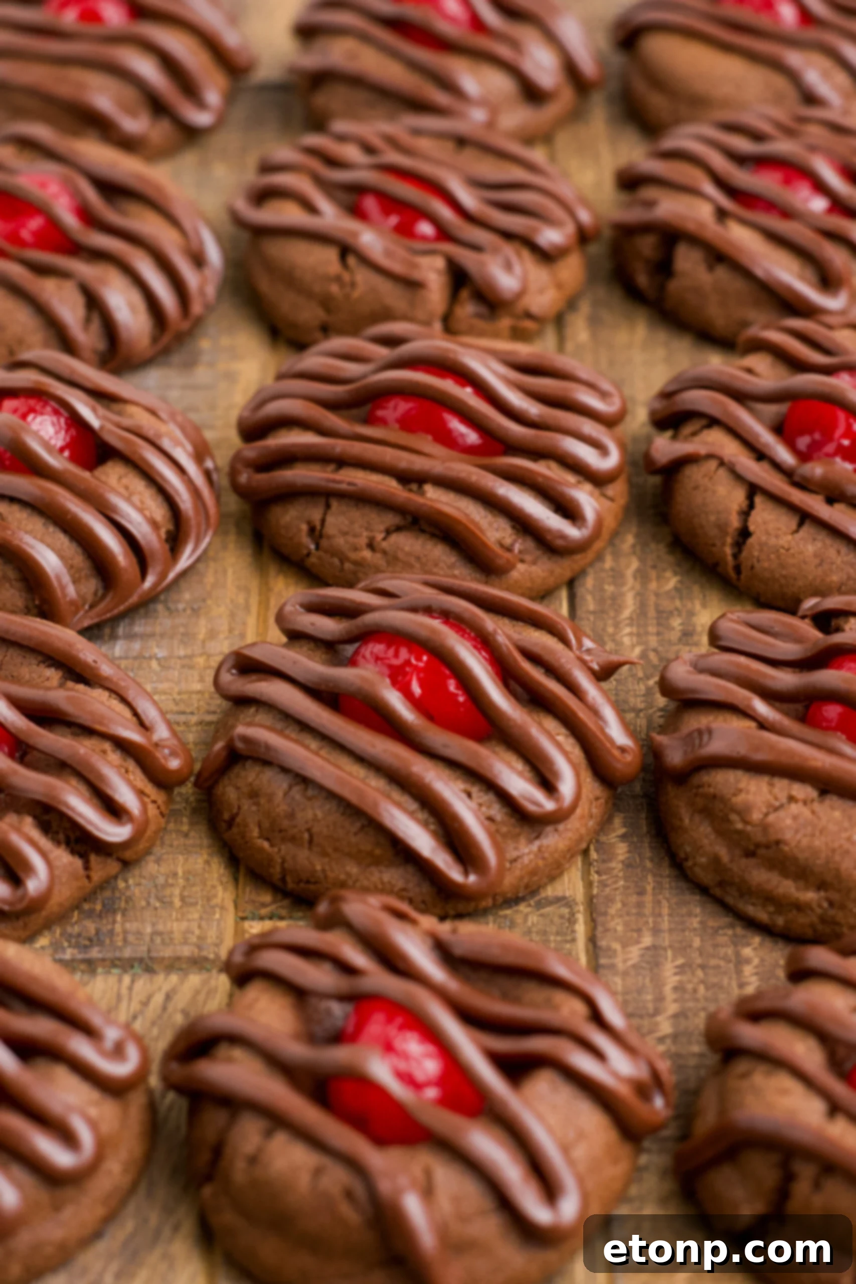 A perfectly arranged line of Chocolate Cherry Cookies on a dark wood background, showcasing their uniform shape and appealing chocolate drizzle, ready for serving or storage.