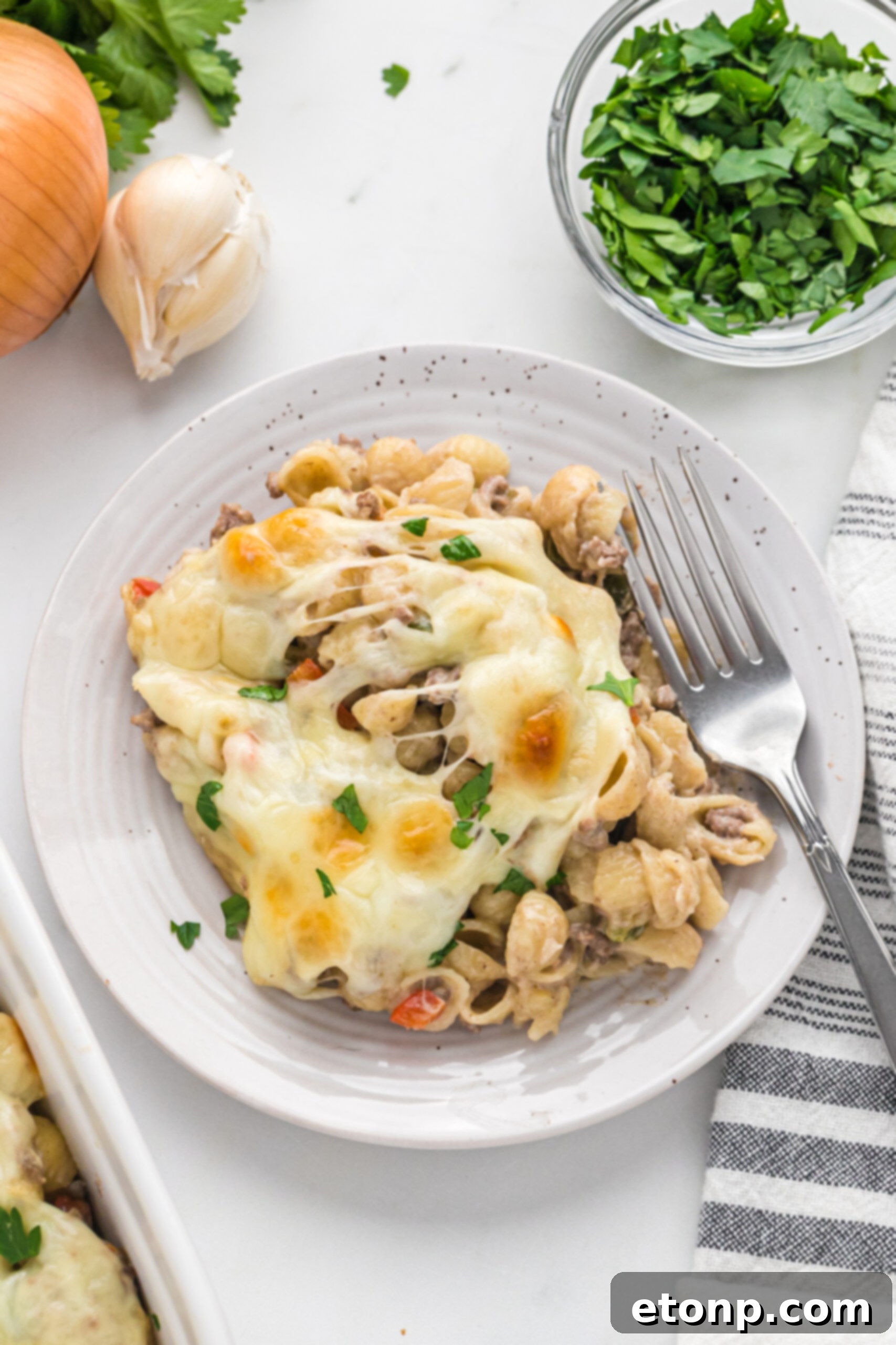 Overhead view of Philly Cheesesteak Casserole on a white dish served with a silver fork.