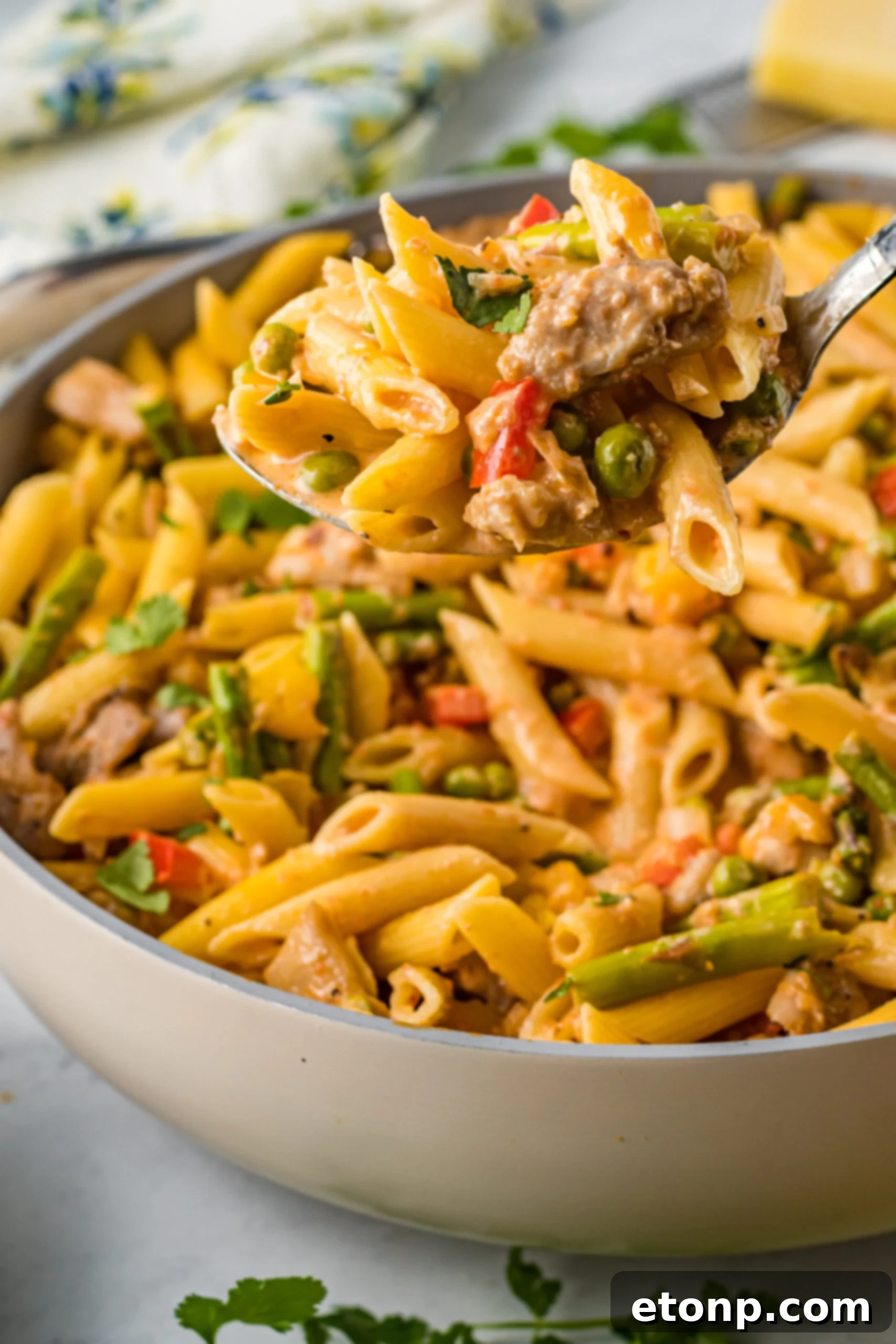 Side view of Cajun Chicken Pasta with a large spoon scooping out a bite